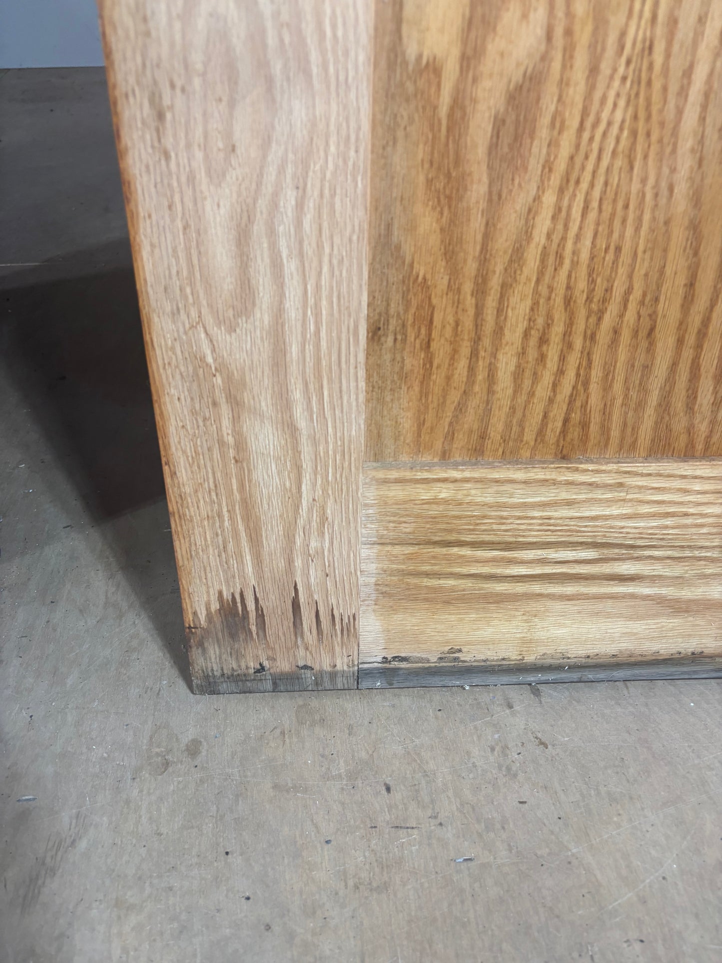 Close-up of a wooden surface with visible grain and texture on a concrete floor.