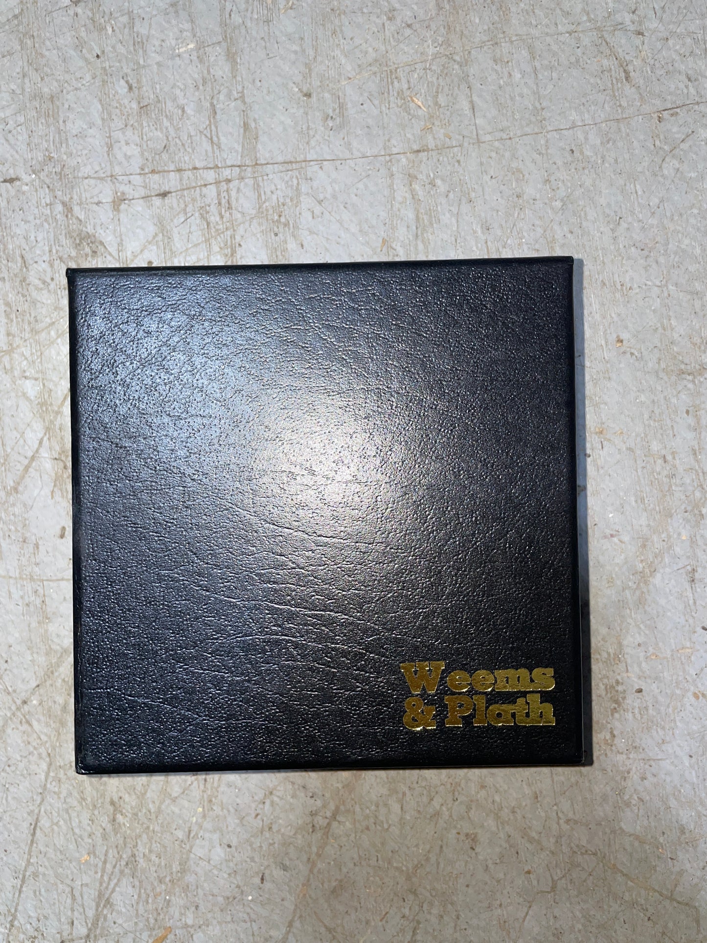Black leather-bound book with gold embossed text on a textured surface