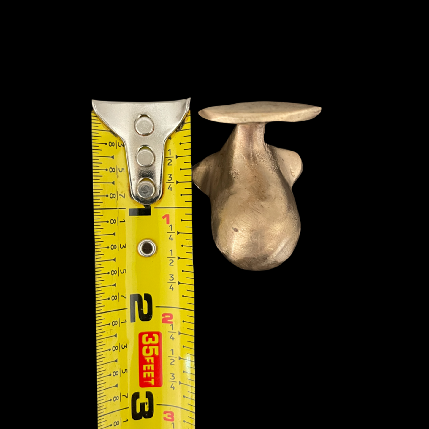 Metallic object next to a measuring tape on a black background