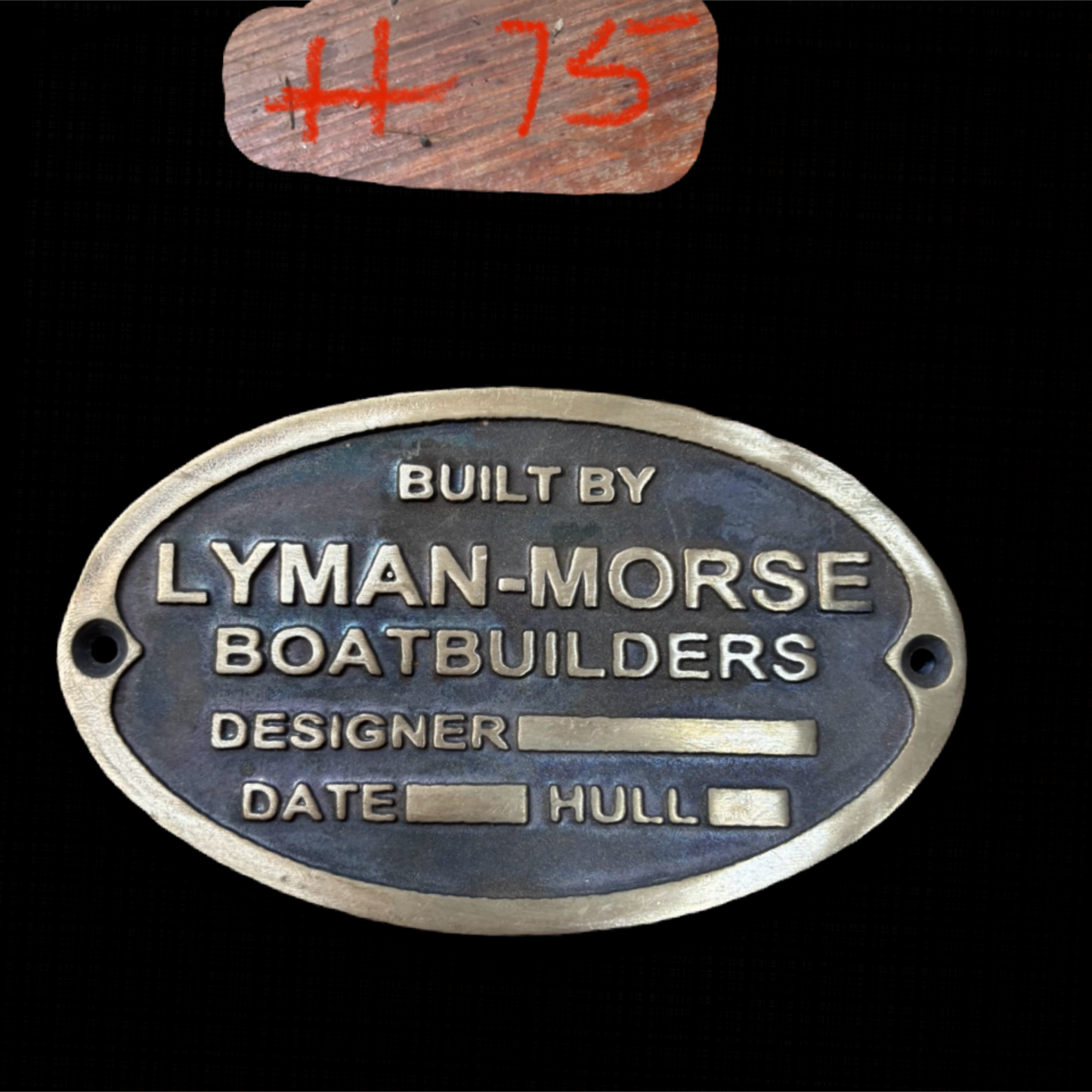 Metal plaque with 'Built by Lyman-Morse Boatbuilders' text on a black background