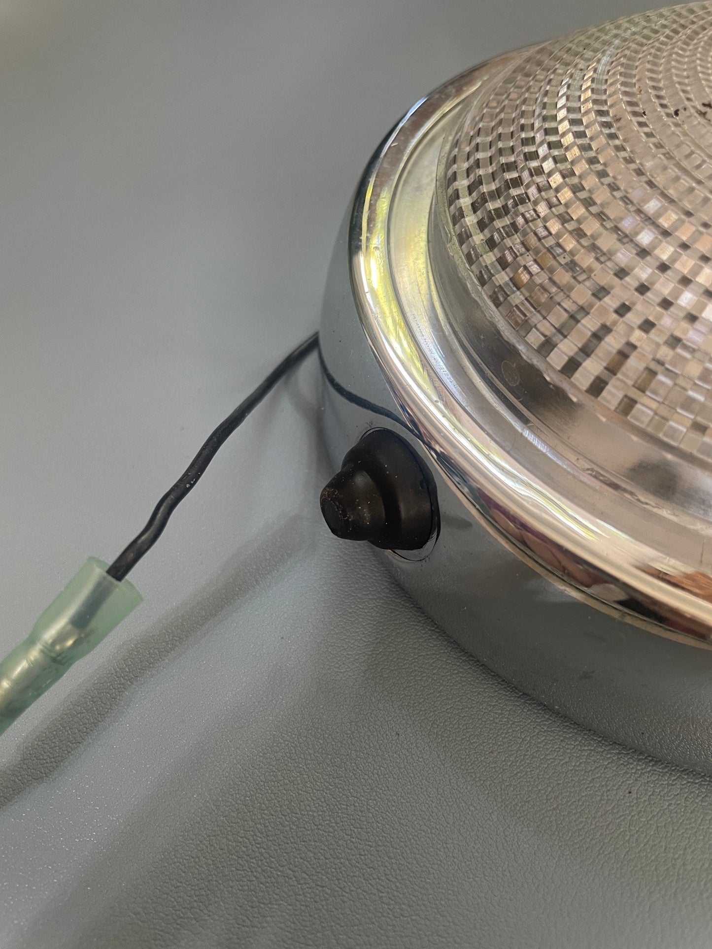 Close-up of a metallic object with a wire attached on a gray background