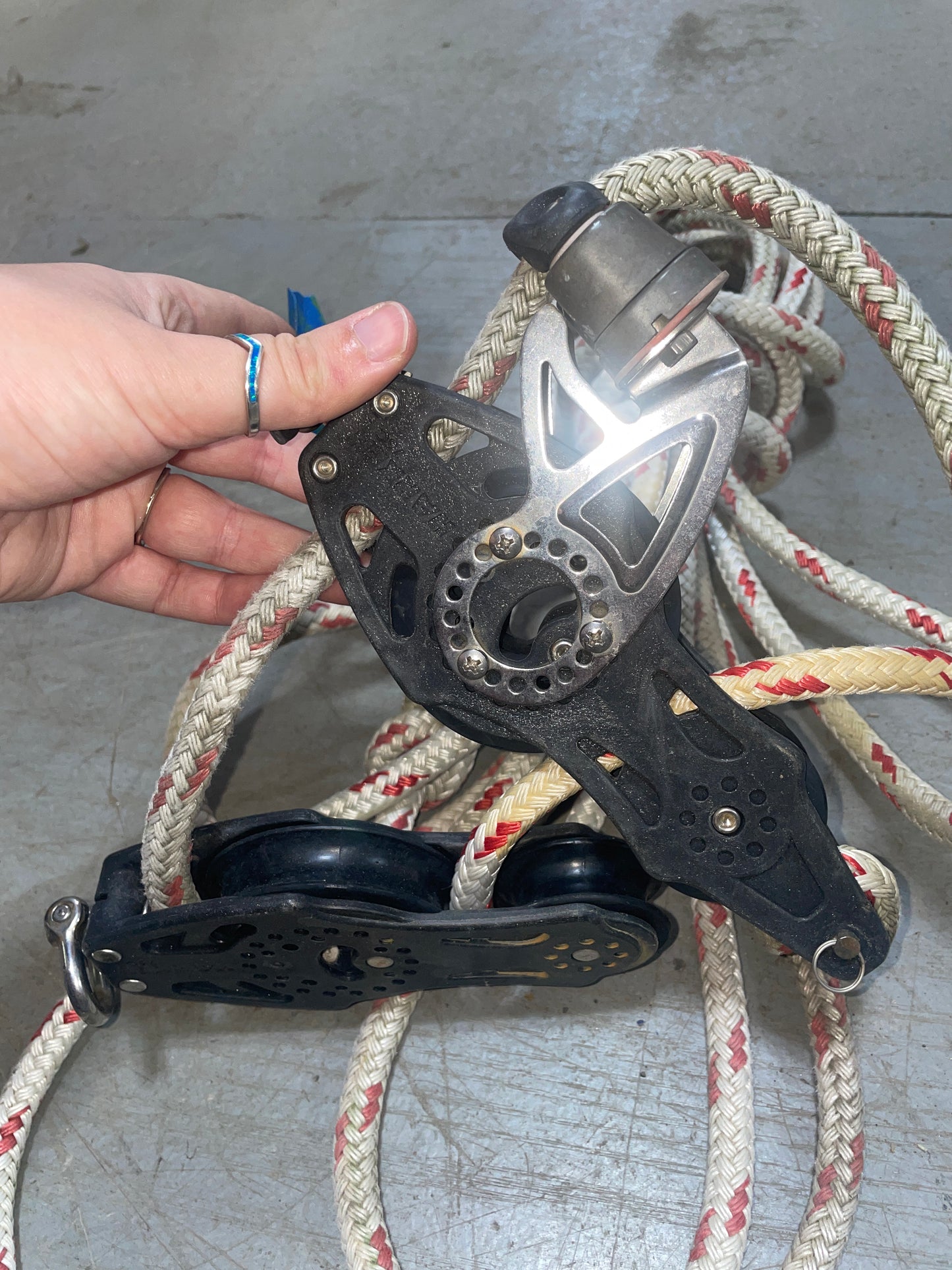 Hand holding a pulley system with ropes against a concrete wall.