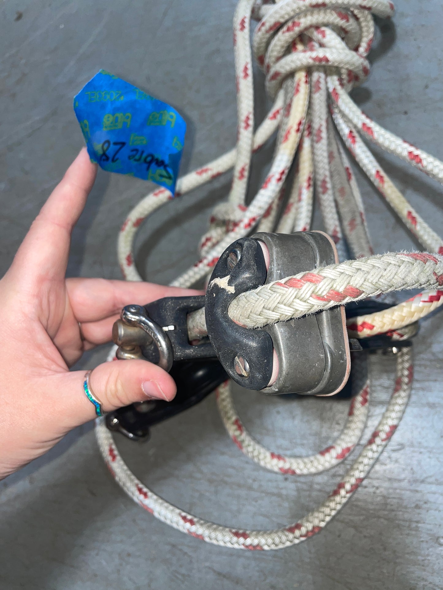 Hand holding a pulley system with rope against a gray background