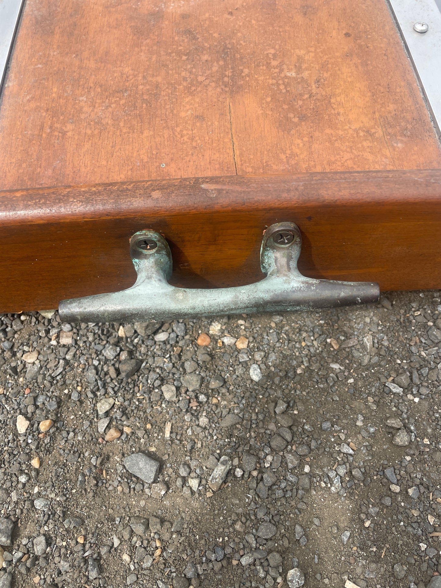 Metal bracket on a wooden surface with a concrete floor background