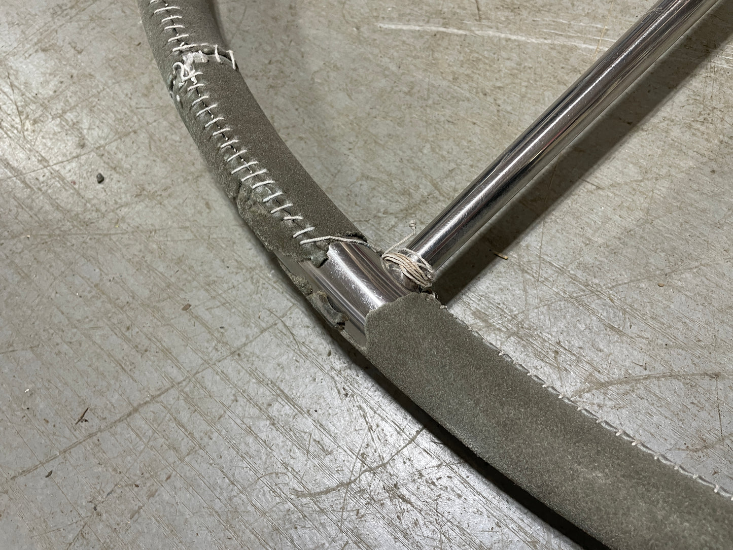 Close-up of a metal pipe with a hose attached on a concrete floor.