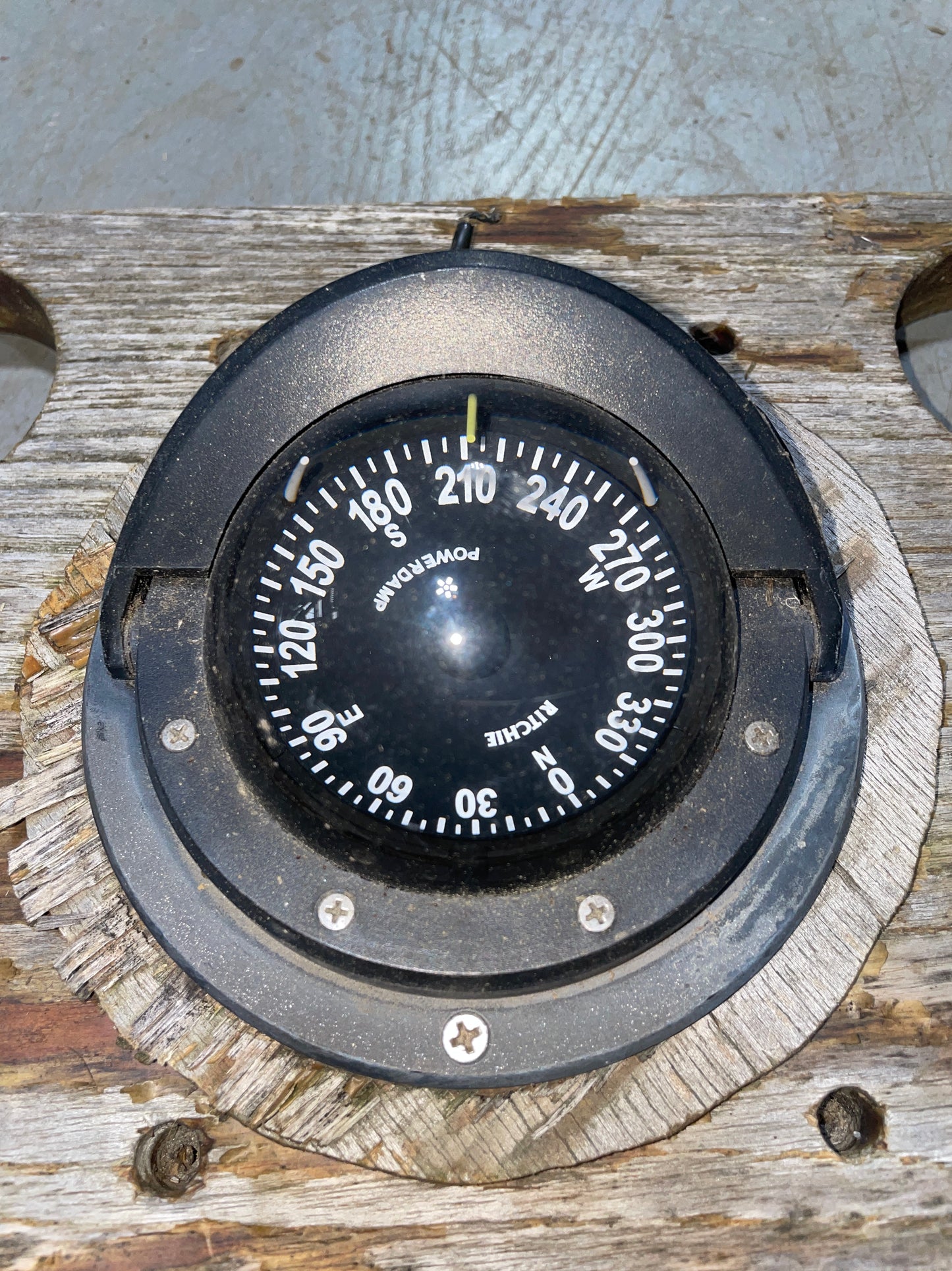Compass on a wooden panel with visible wear