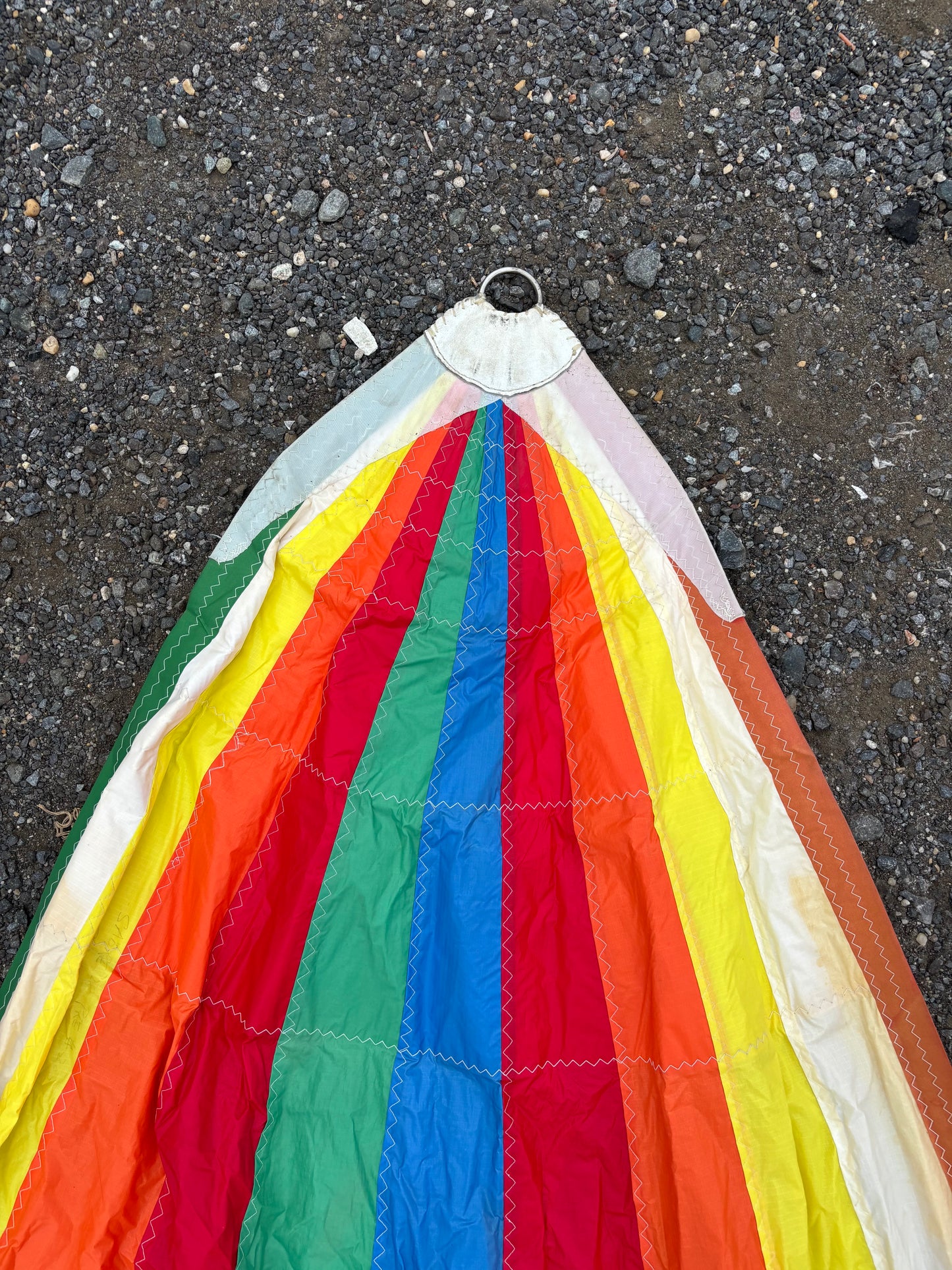 Corner of a colorful kite on a dark asphalt surface