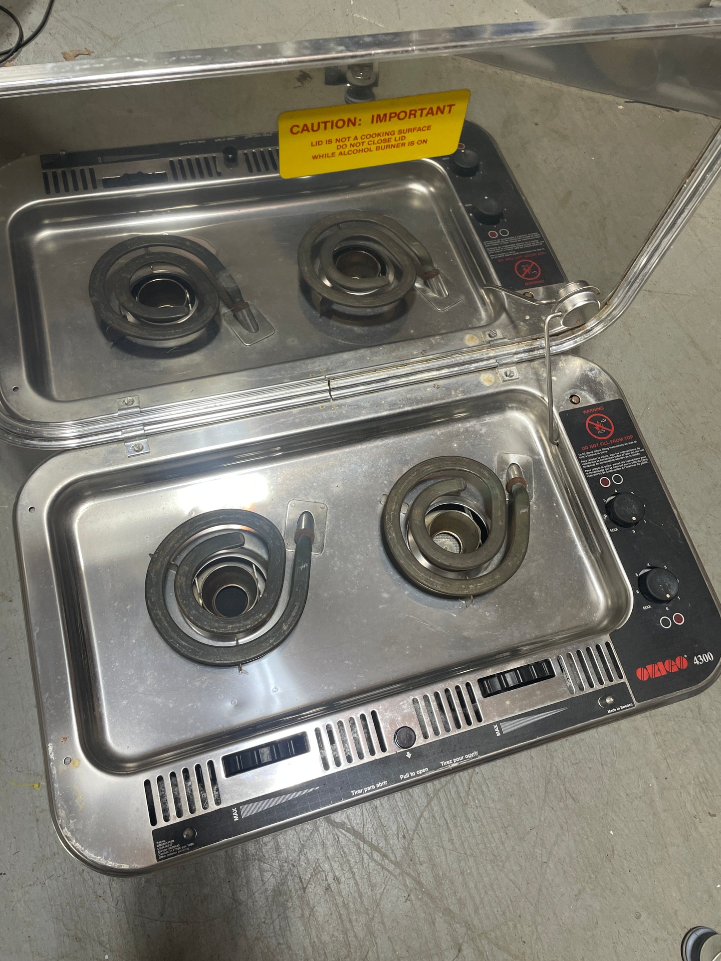 Stainless steel gas stove with four burners on a gray surface