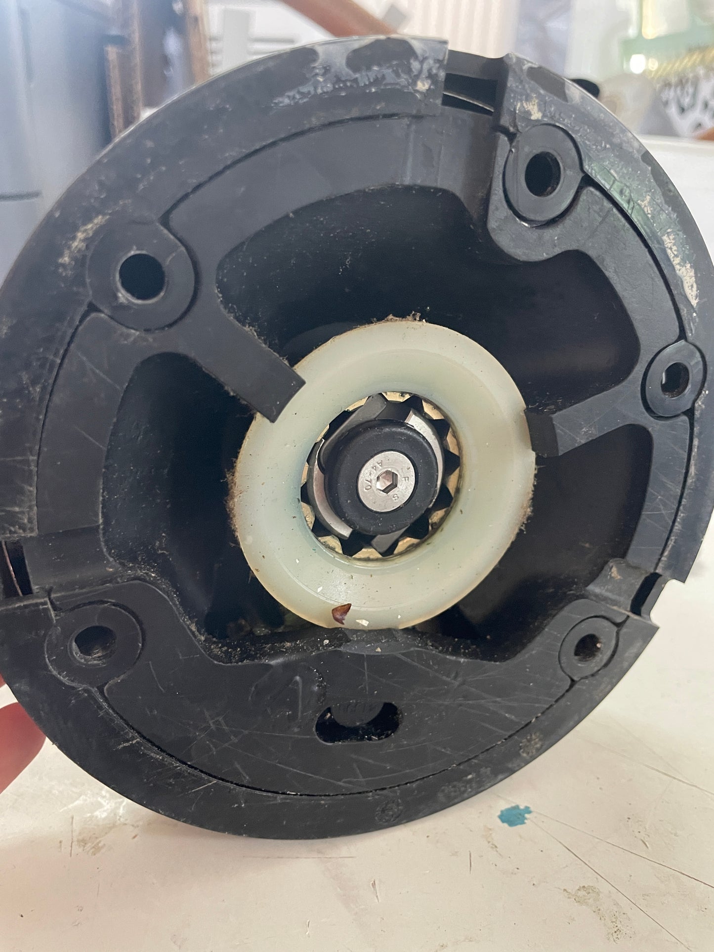 Close-up of a mechanical component with a black housing and white central wheel.