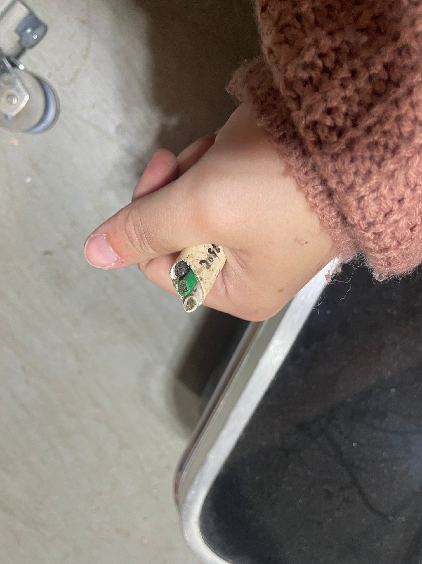 Hand holding a small electronic component near a metal surface