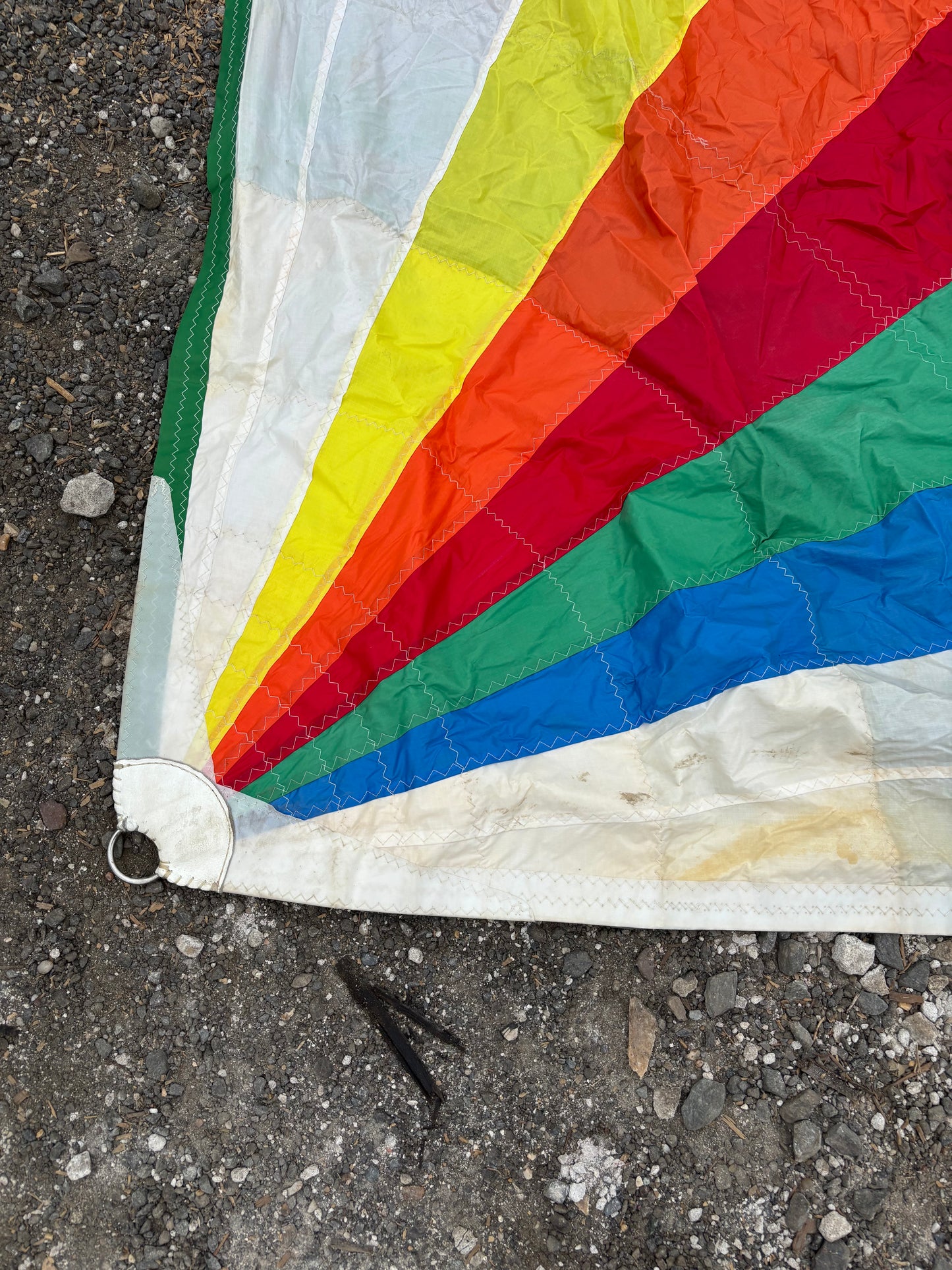 Colorful kite with rainbow pattern lying on a concrete surface