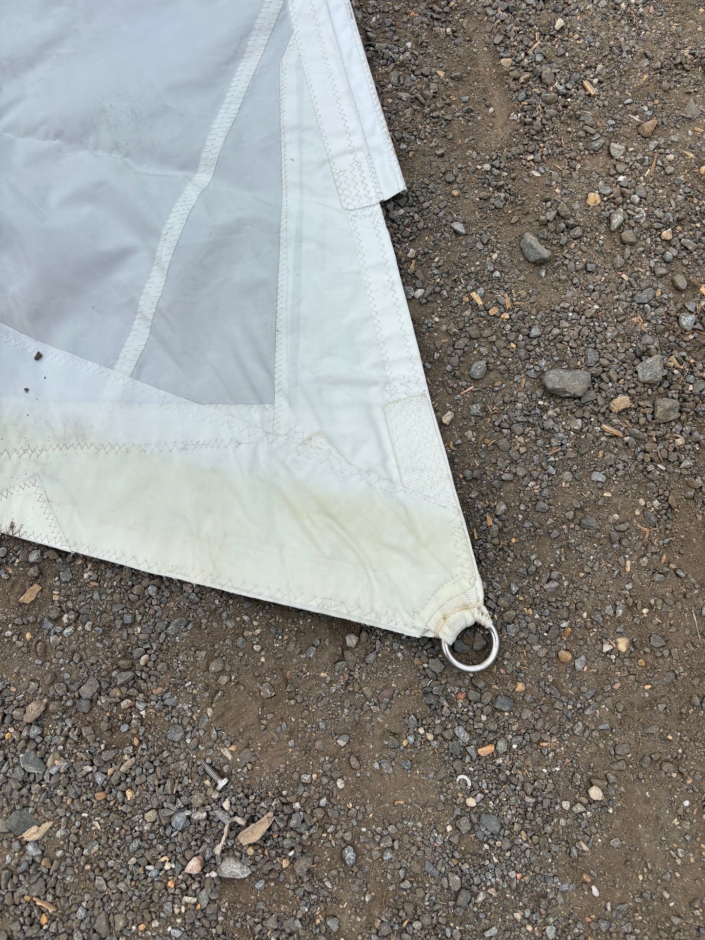 Corner of a white tarp on a gravel surface
