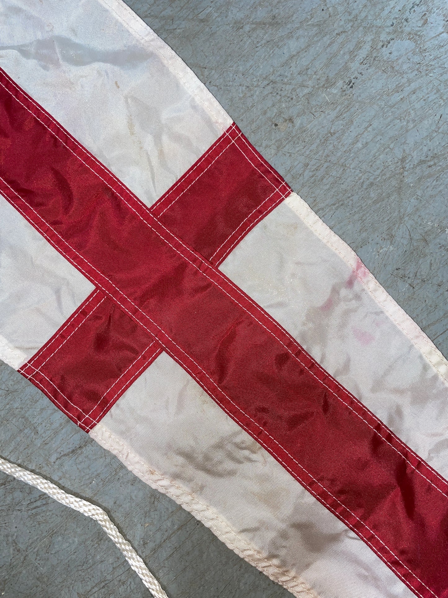 Flag with a red cross on a white background, lying on a gray surface.