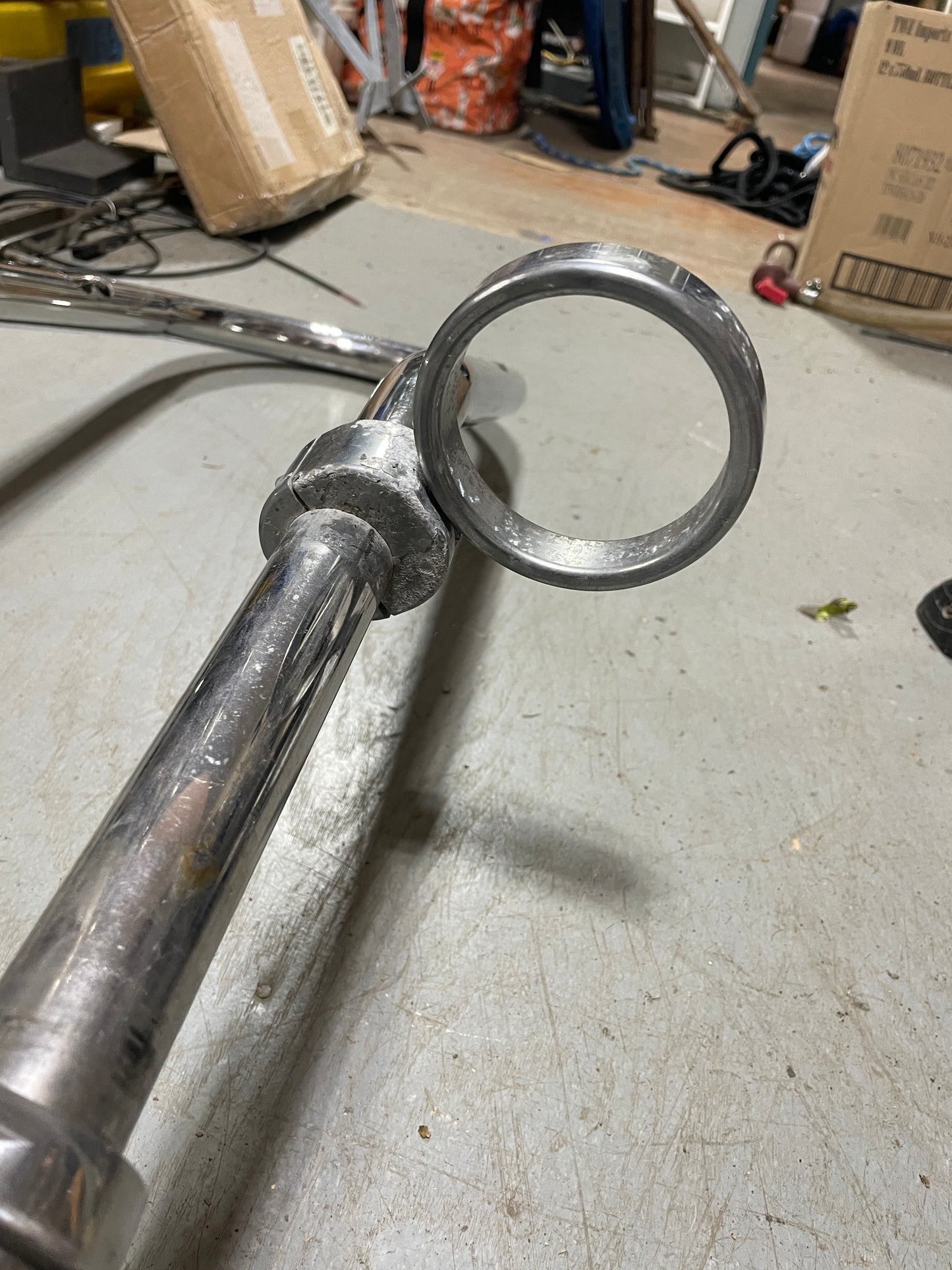 Metallic lever or handle on a concrete floor with tools and boxes in the background