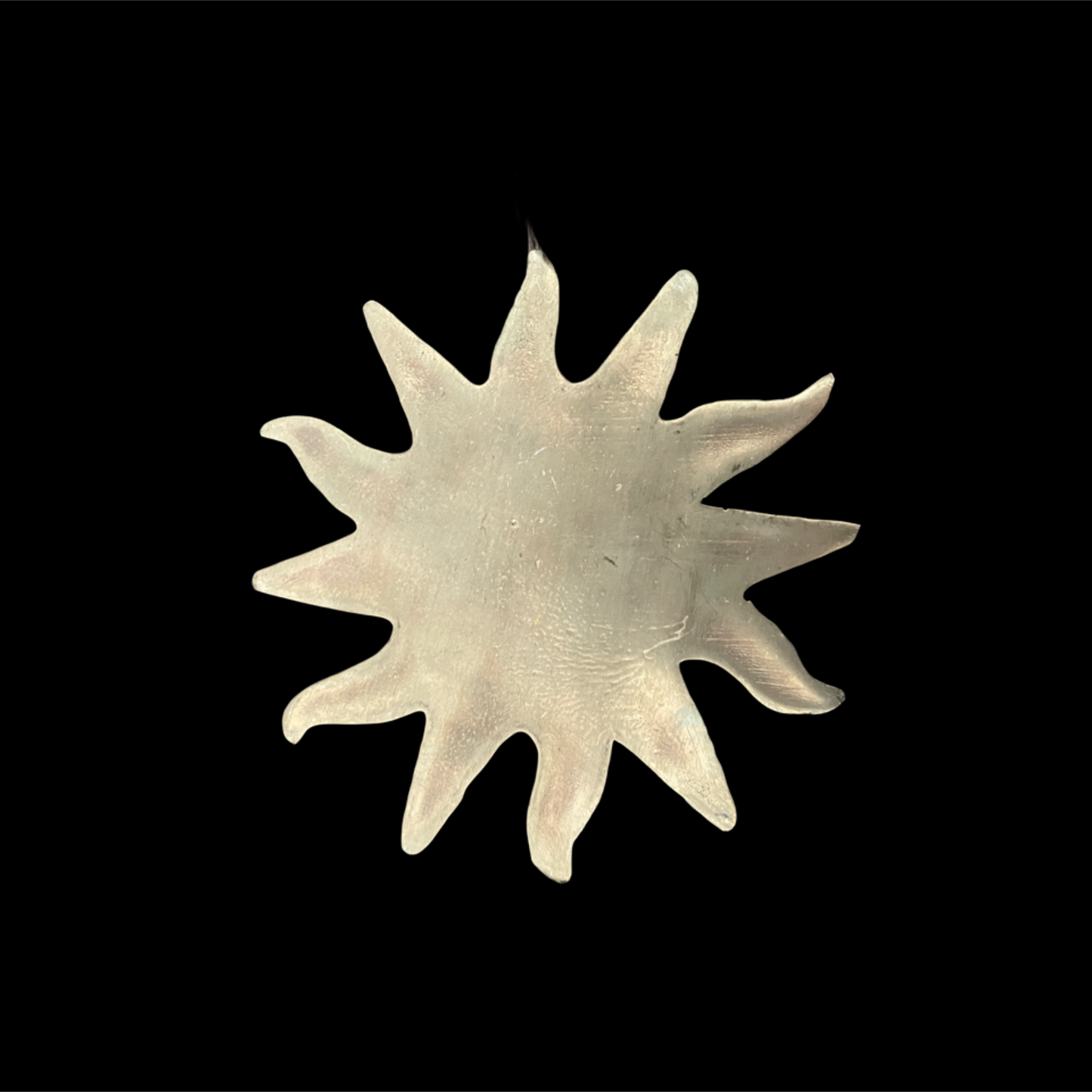 Silver sun-shaped object on a black background
