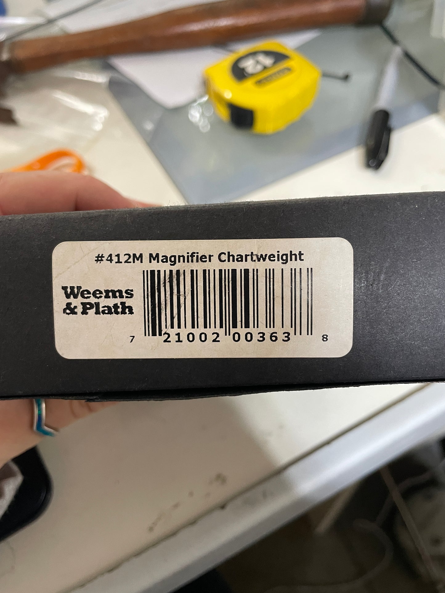 Bar code label on a product with 'Weems & Plath' branding, held in a hand.