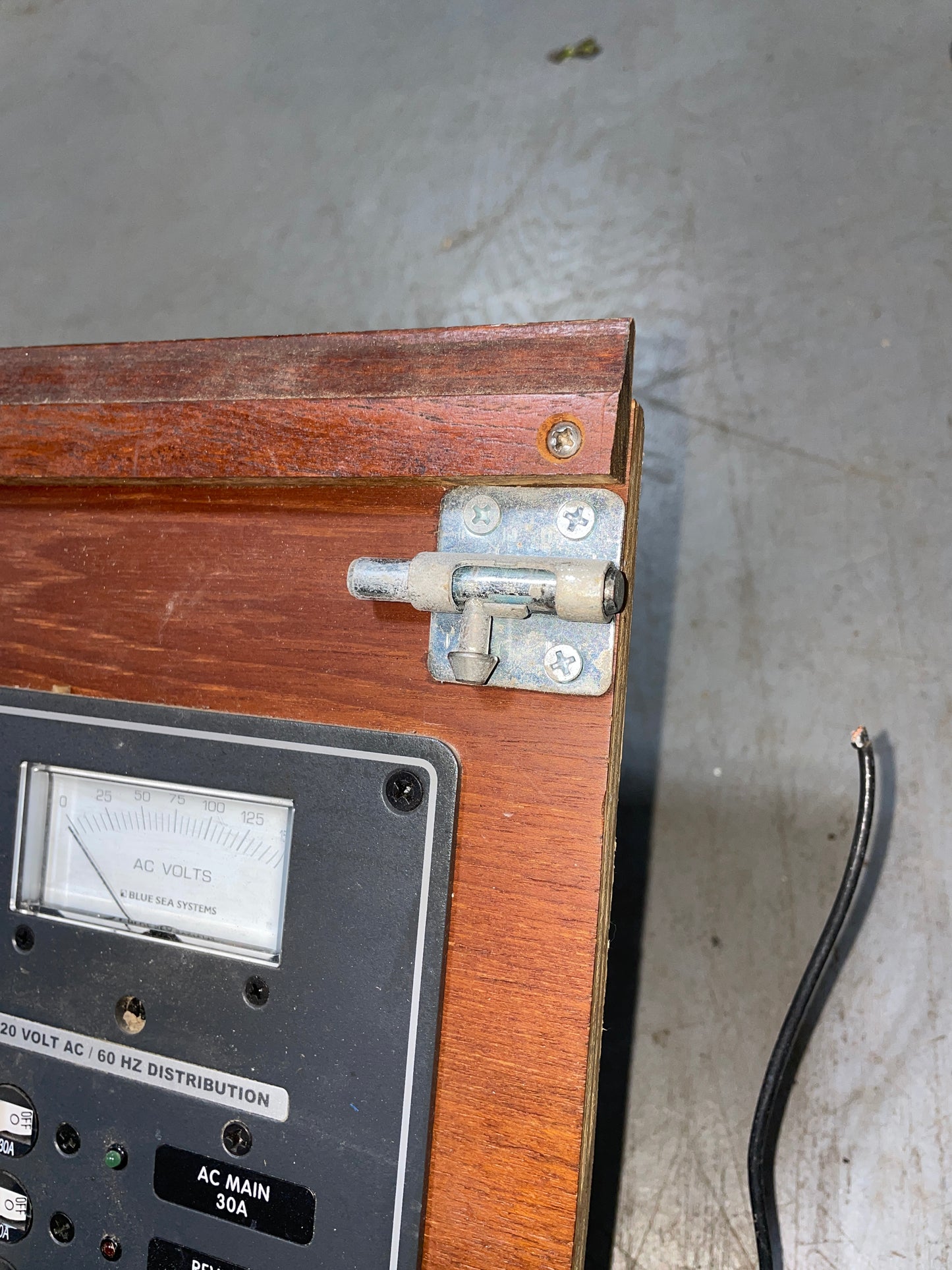 Close-up of a wooden electrical panel with metal bracket and wiring.