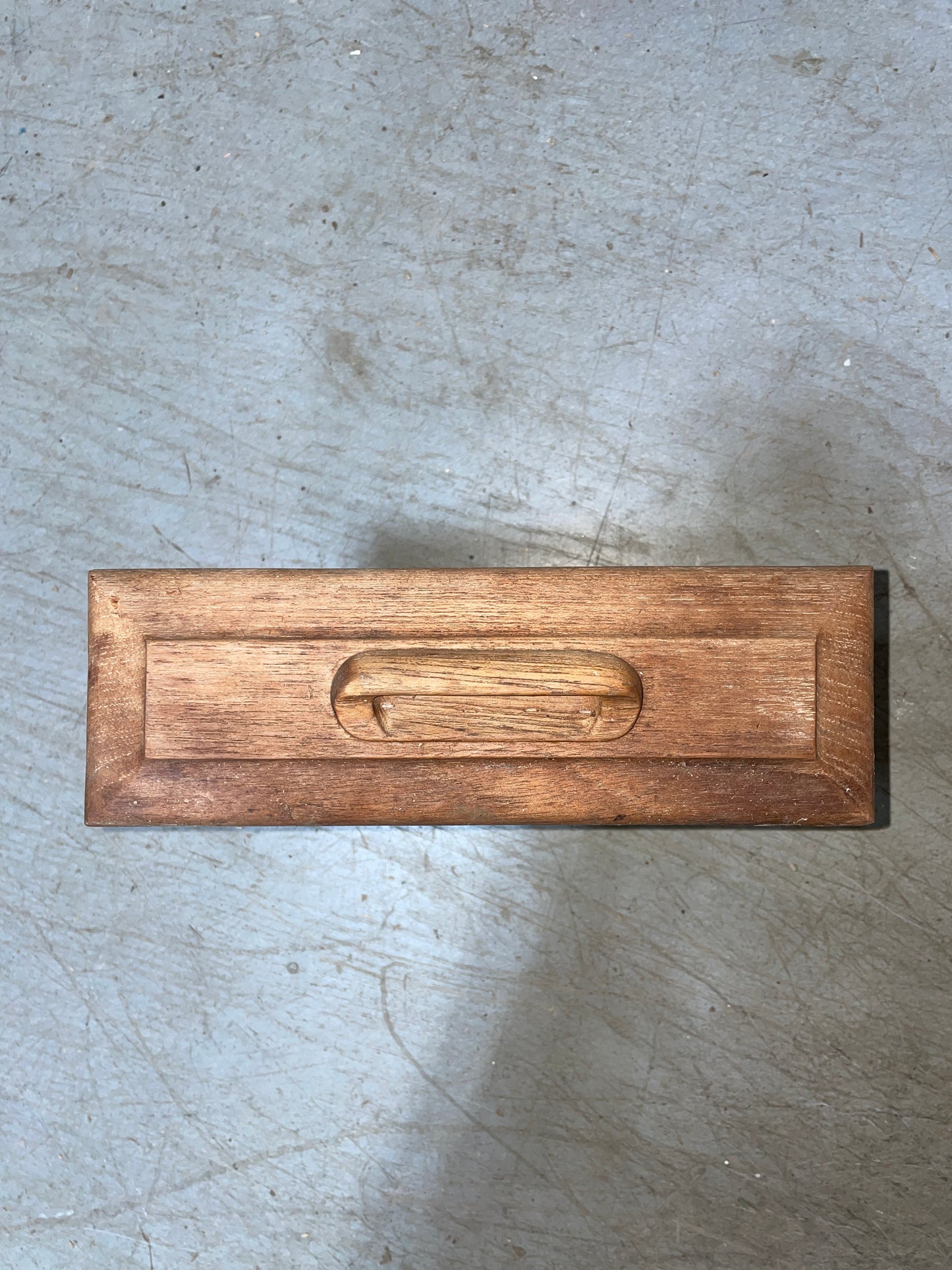 Wooden pull handle on a concrete surface