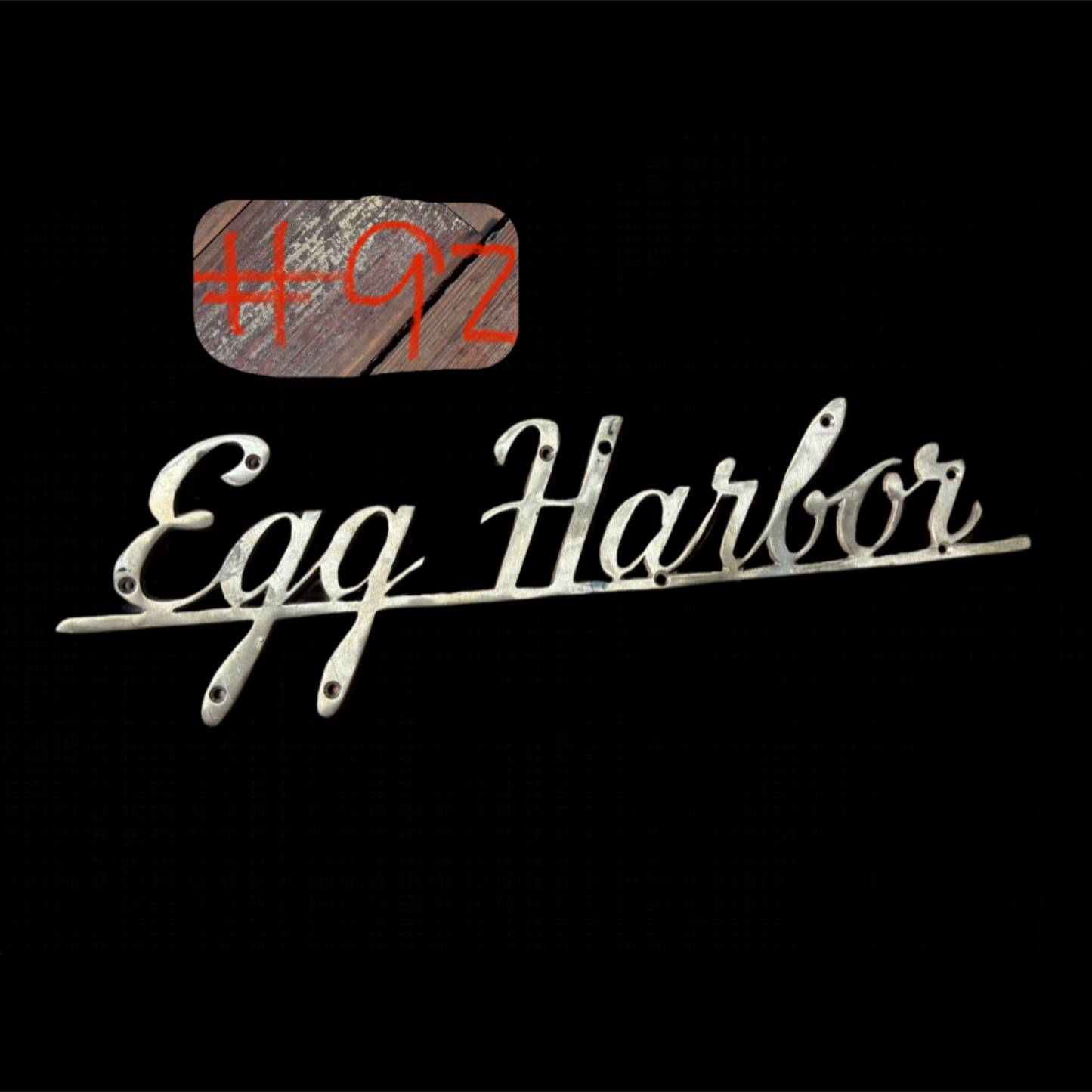Decorative metal sign with 'Egg Harbor' text on a black background
