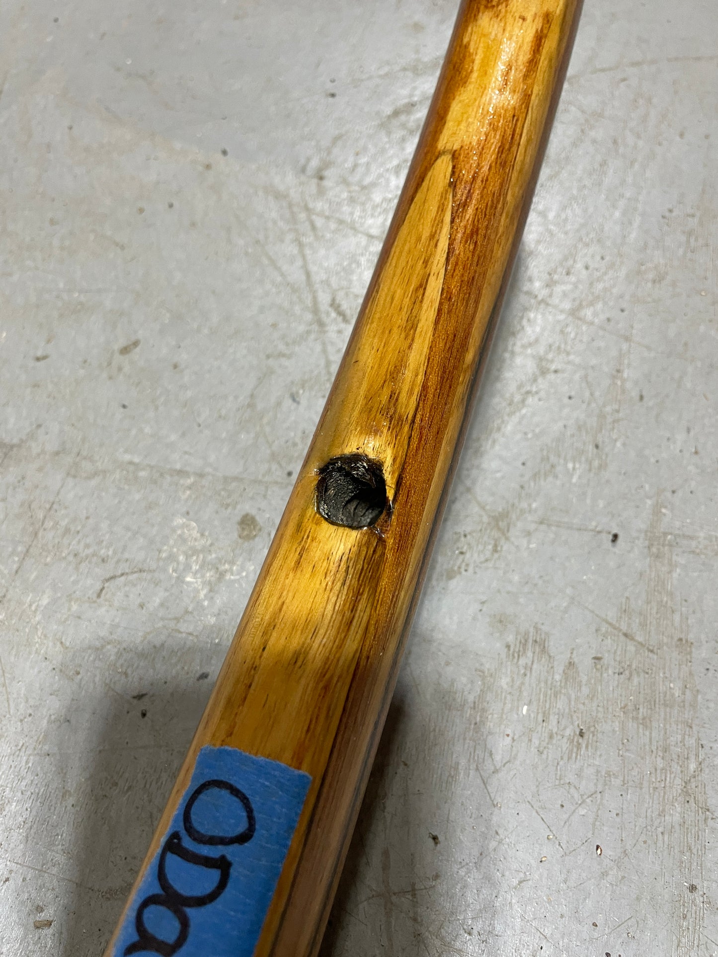 Wooden stick with a hole and blue label on a gray surface