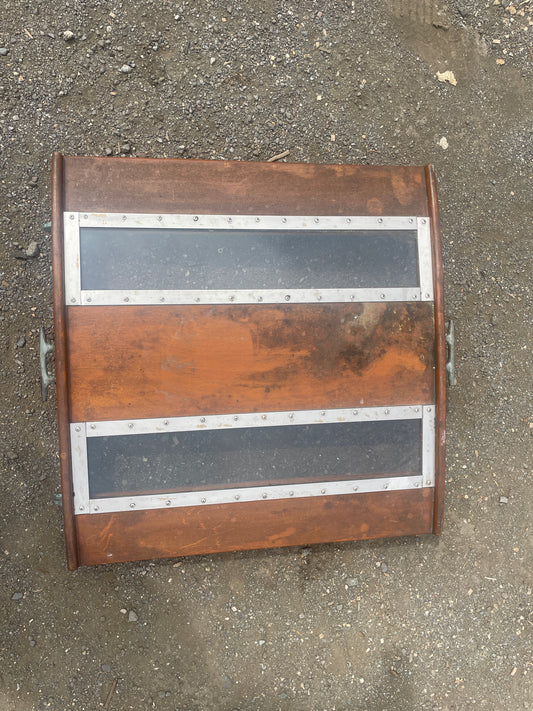 Rust-colored metal object with silver straps on a concrete surface