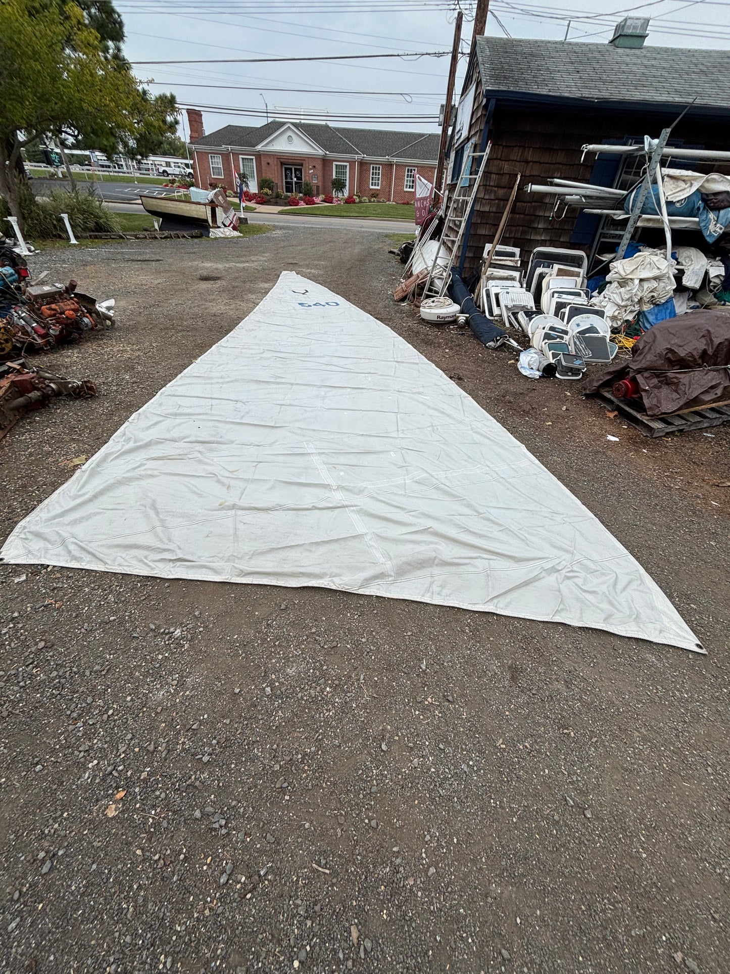 Large white sail on a street with buildings and people in the background