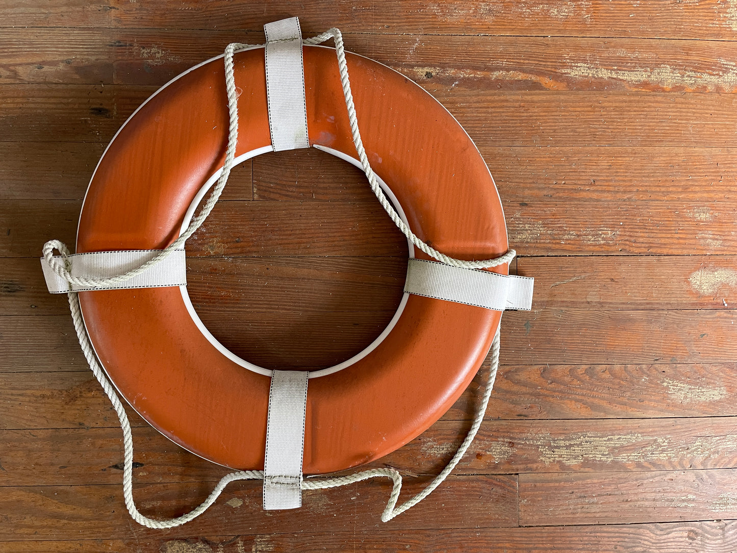 Life buoy with white rope on a wooden surface