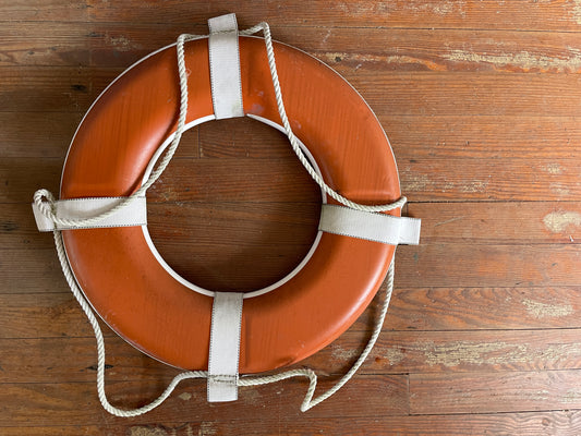 Life buoy with white rope on a wooden surface