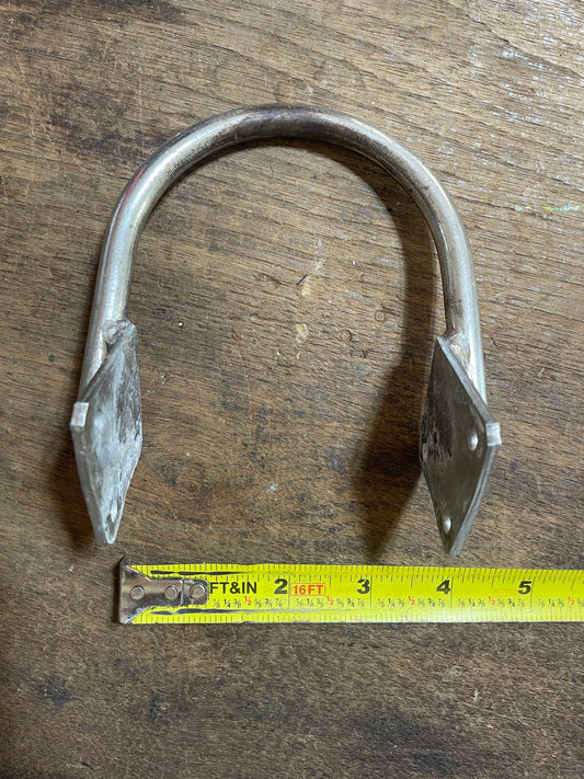 Metal U-shaped bracket on a wooden surface with a measuring tape for scale.