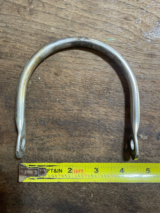 Metal U-shaped bracket on a wooden surface with a measuring tape for scale.