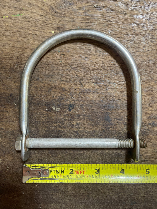 Metal U-bolt with a measuring tape on a wooden surface