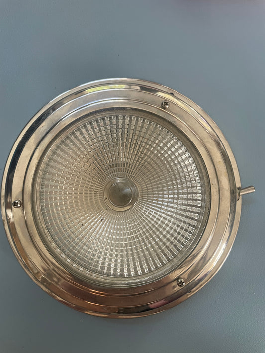 Round metallic light fixture with textured glass cover on a gray background