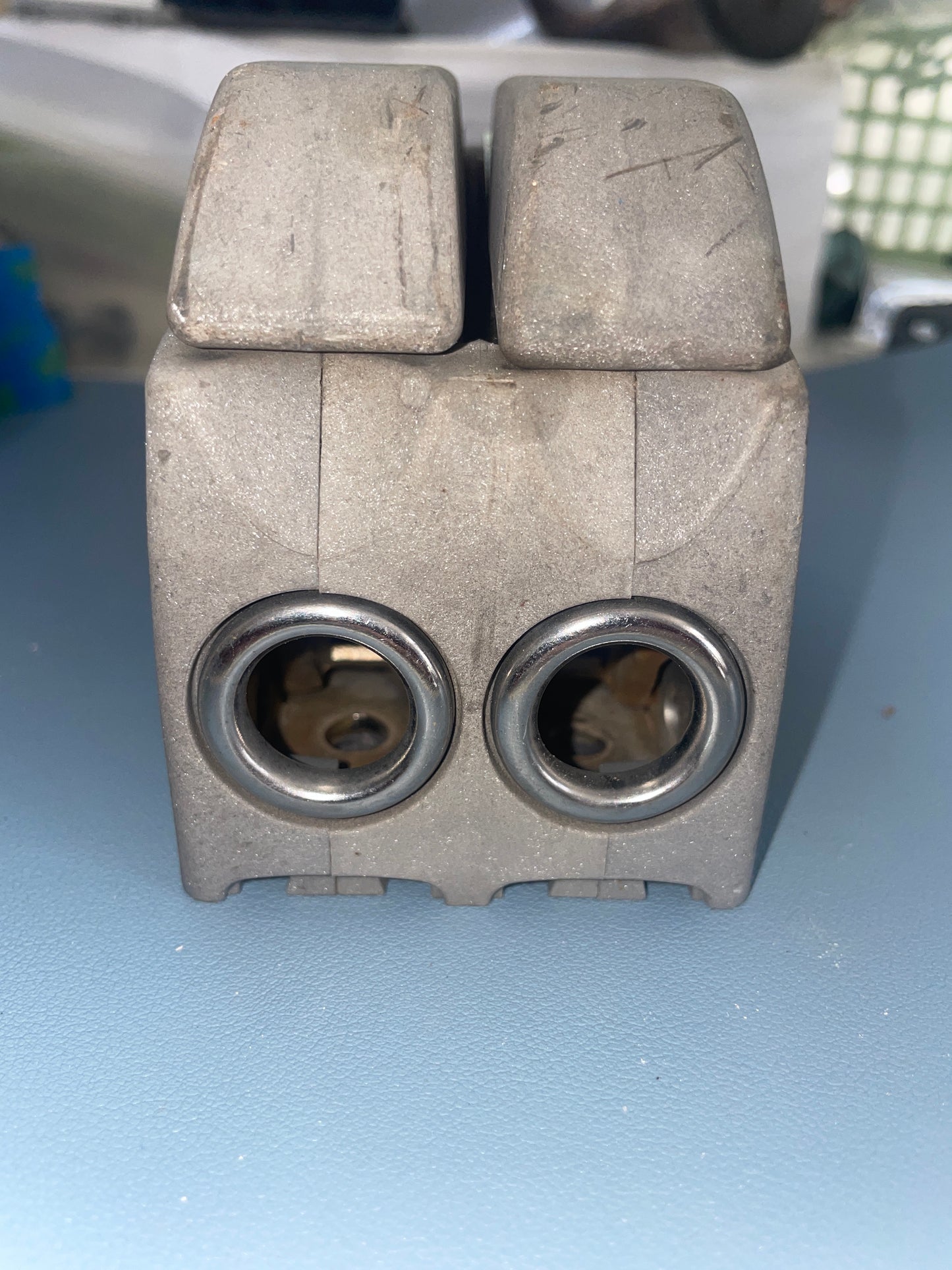 Metal mechanical component with two cylindrical holes on a blue background