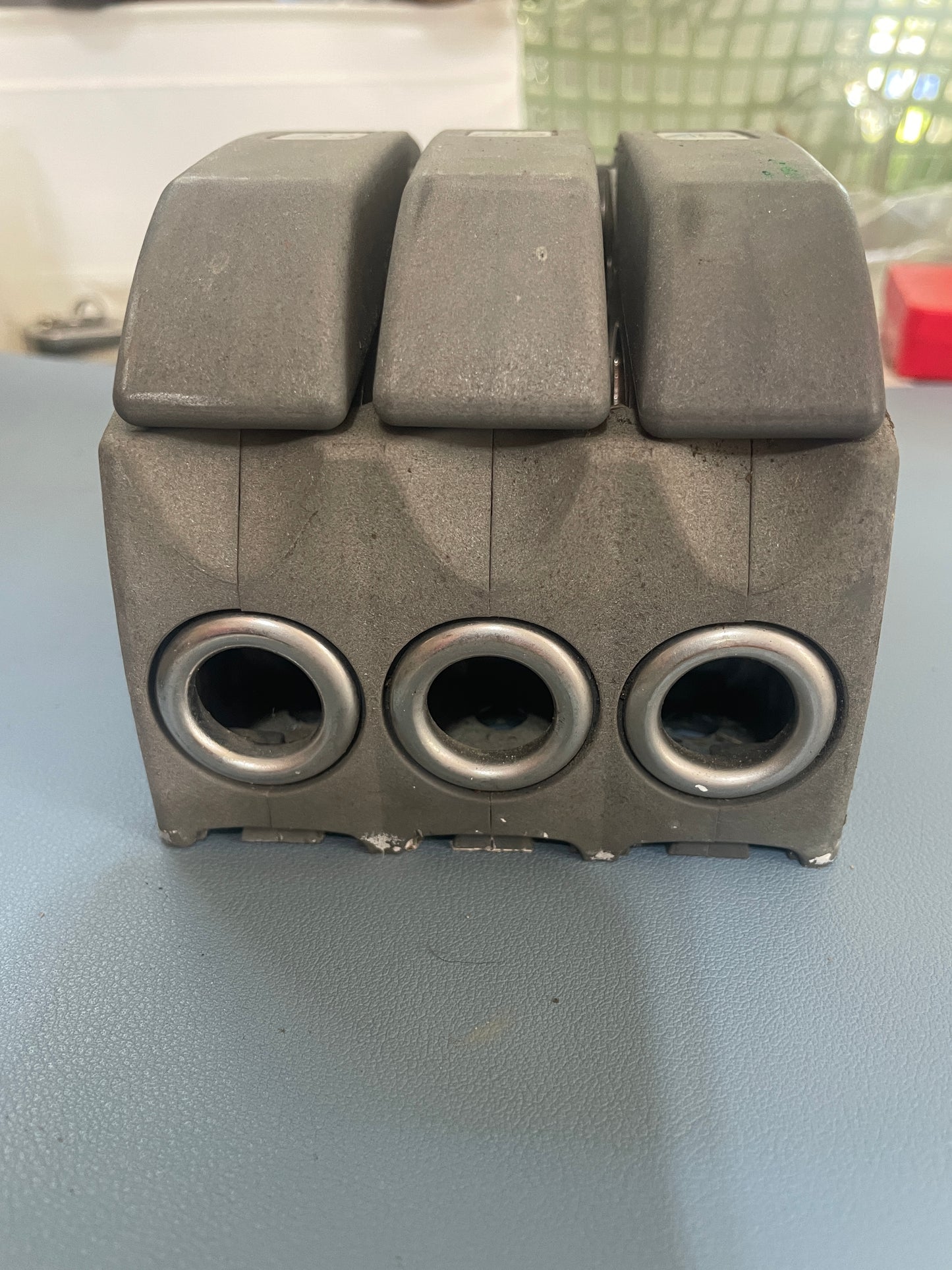 Metallic mechanical component with cylindrical holes on a light gray background
