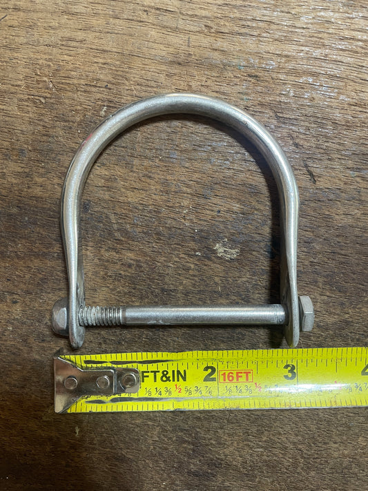 Metal U-bolt with a measuring tape on a wooden surface