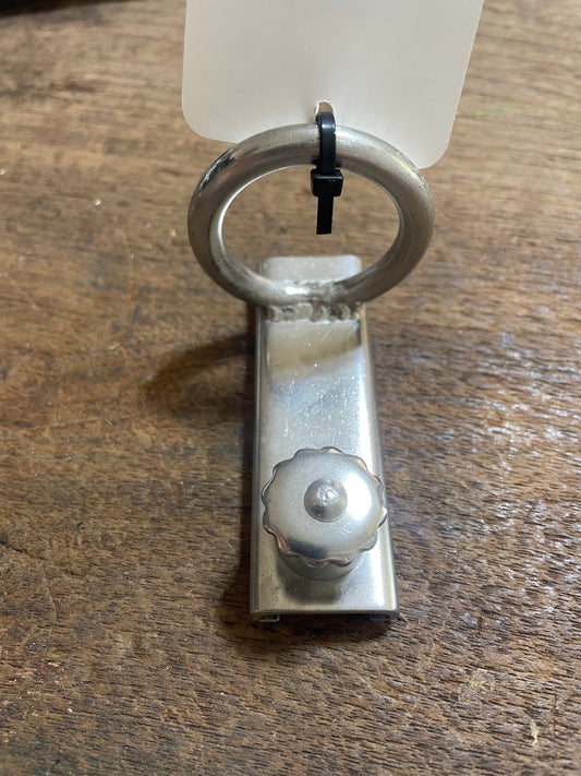 Metal clip with a ring on a wooden surface