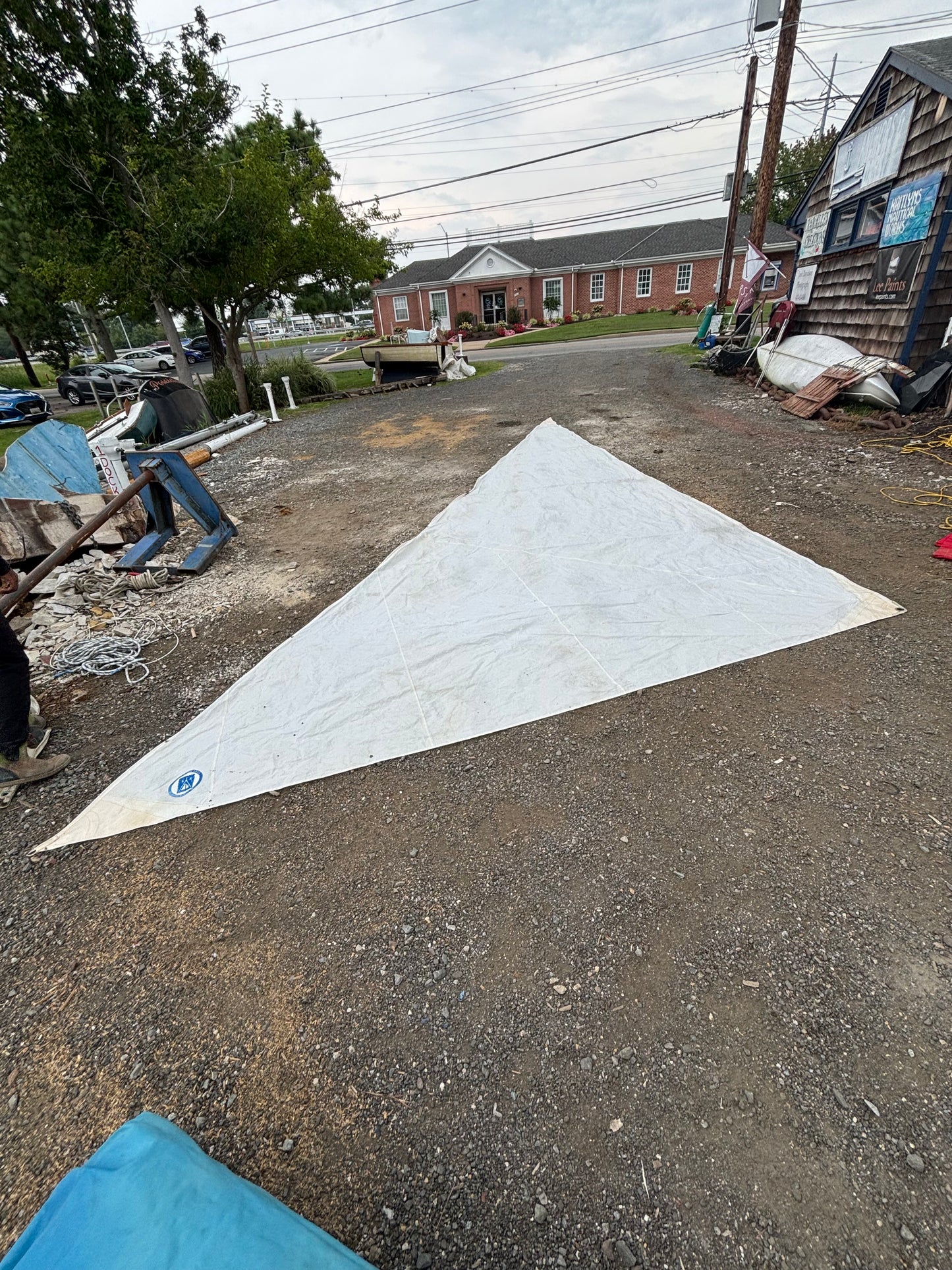 Large white sail on a gravel surface with a residential area in the background