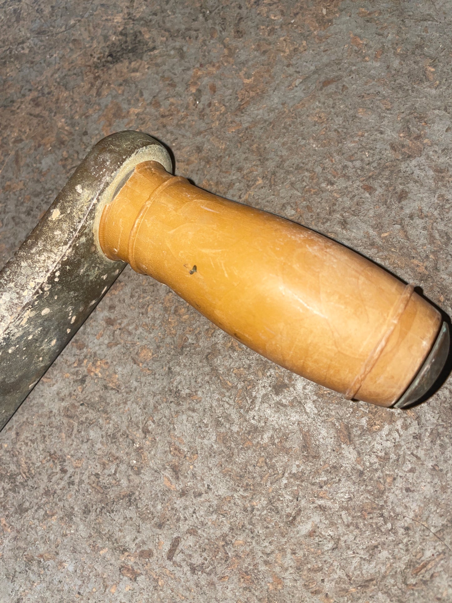Close-up of a tool with a yellow handle on a textured surface
