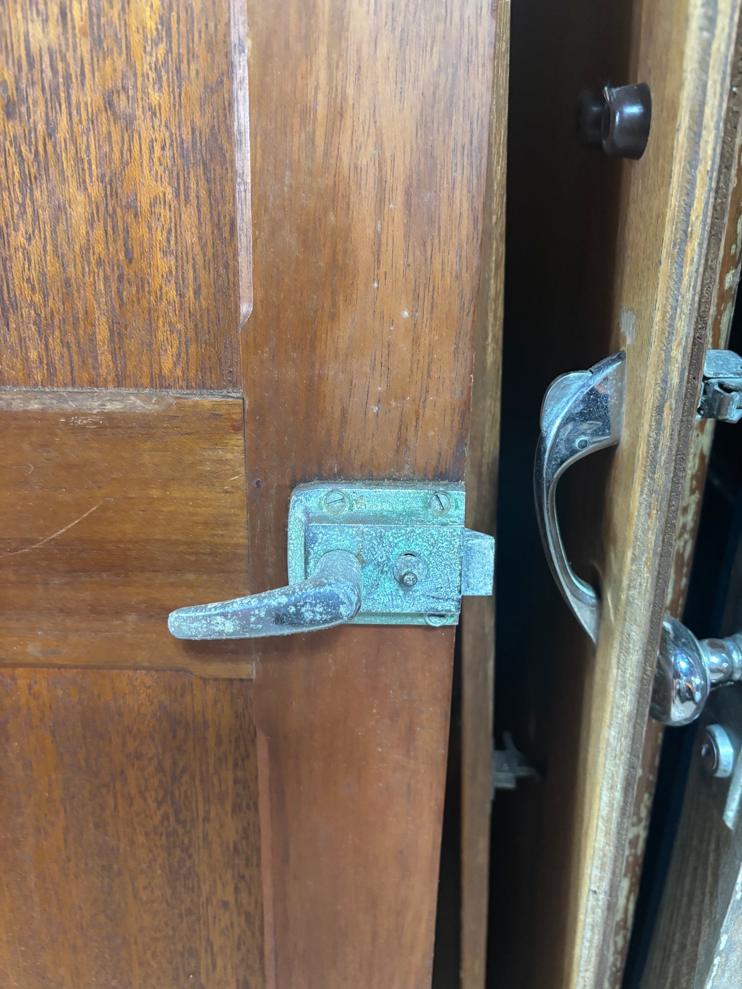 Close-up of a wooden door with metal handles and a latch.