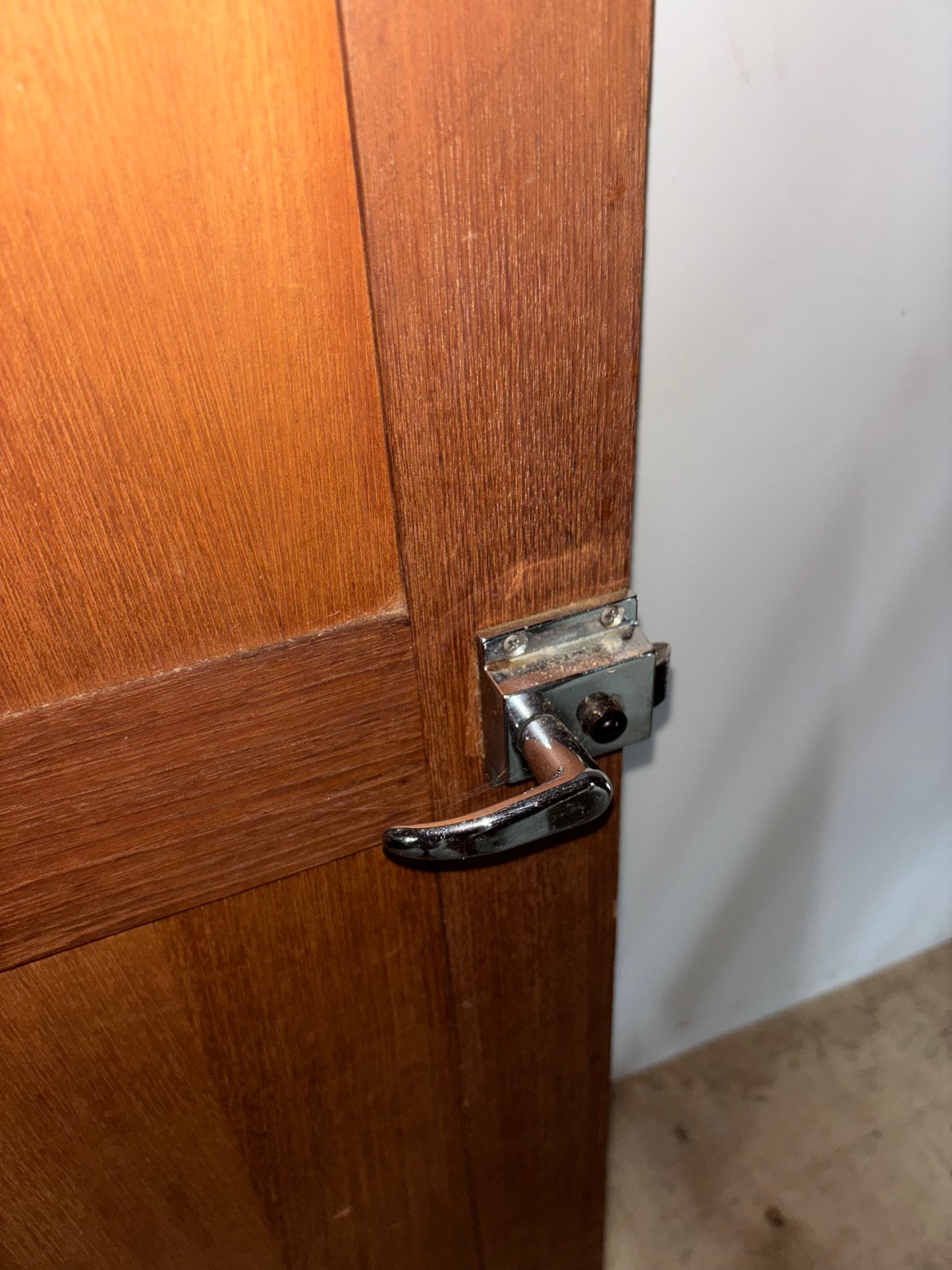 Wooden door with a metal handle and latch on a plain background