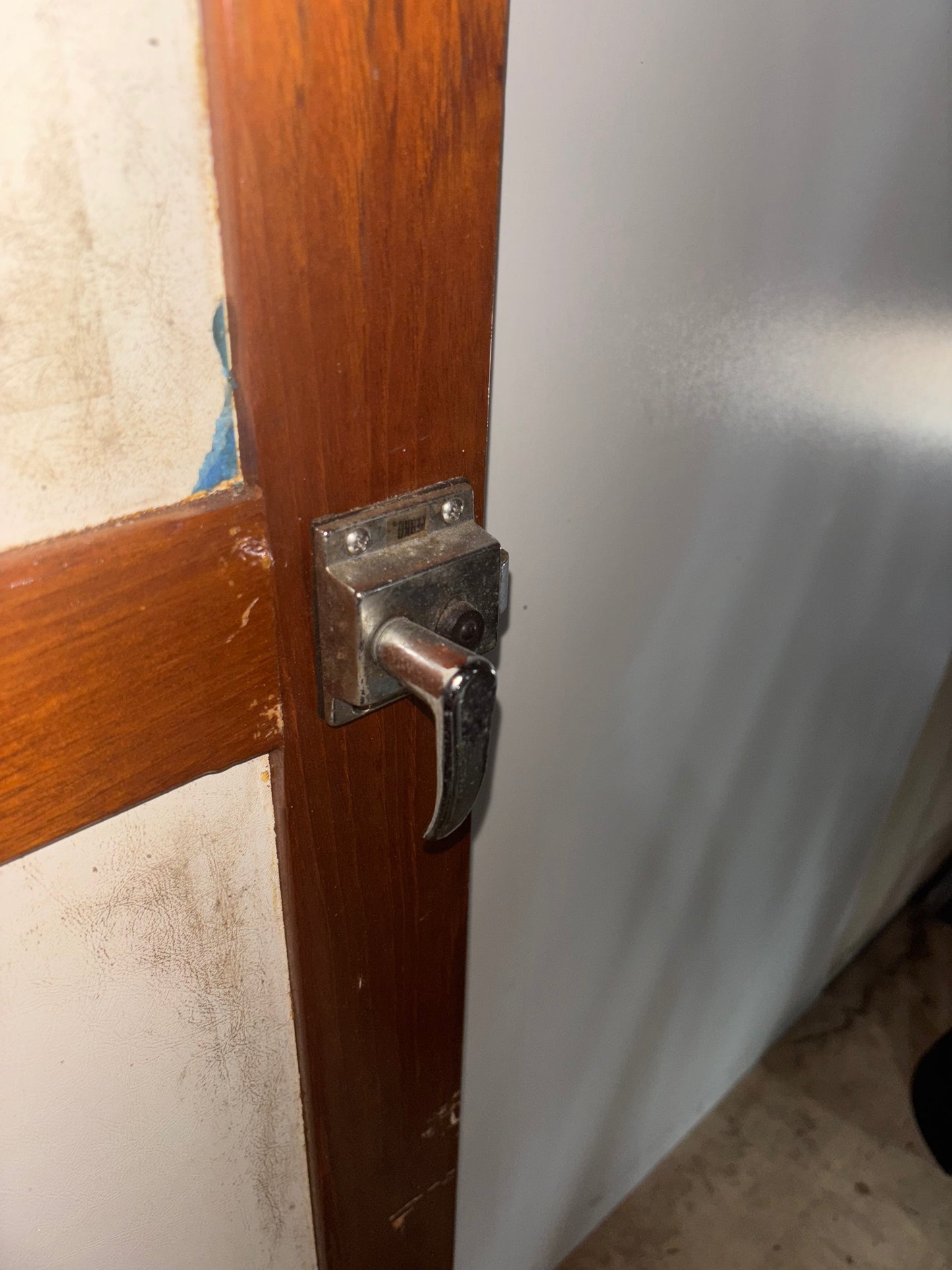Wooden door with metal handle and lock mechanism against a white wall.