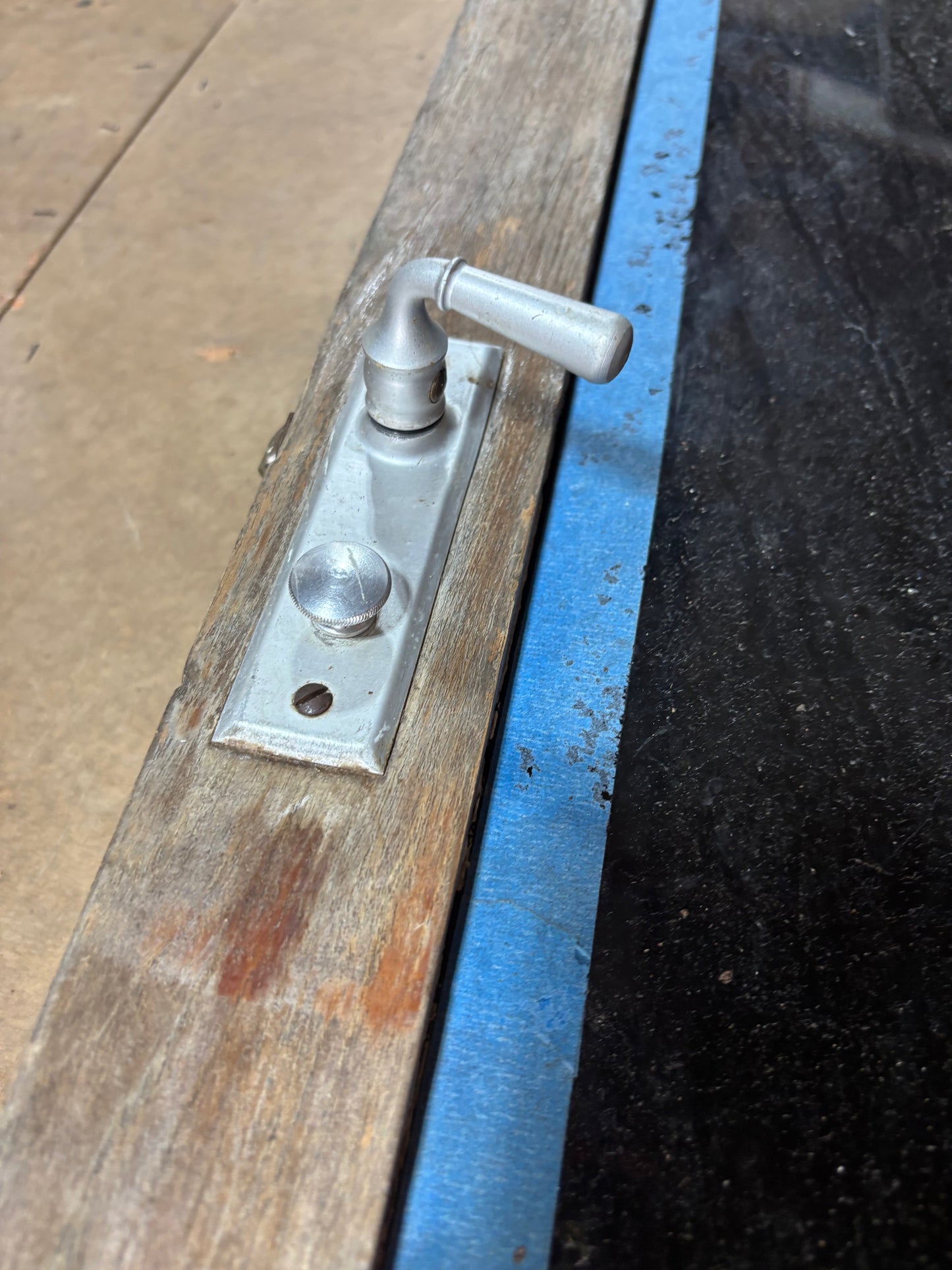 Metal door handle on a wooden door with a blue strap
