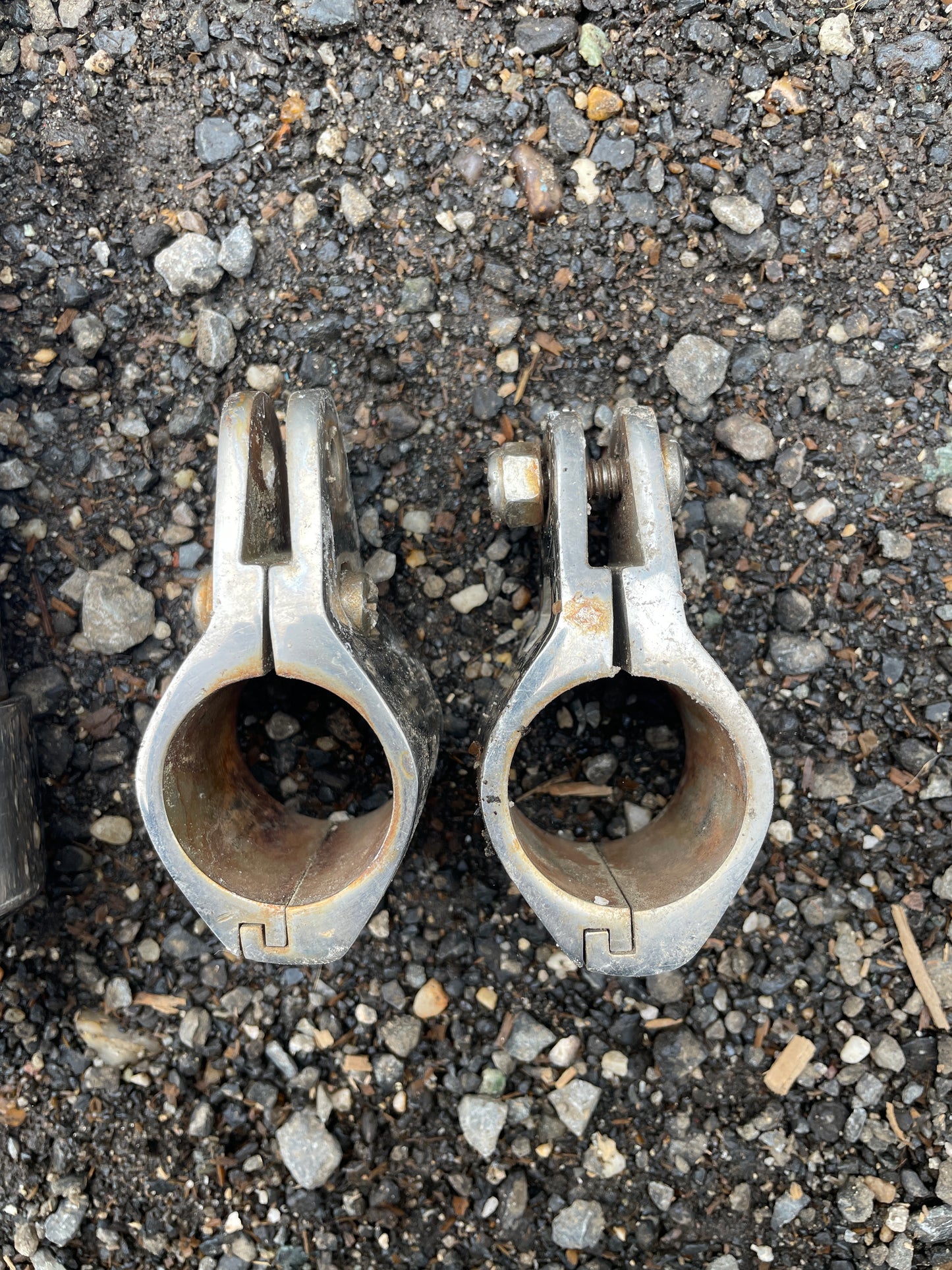 Two metal clamps on a rough asphalt surface
