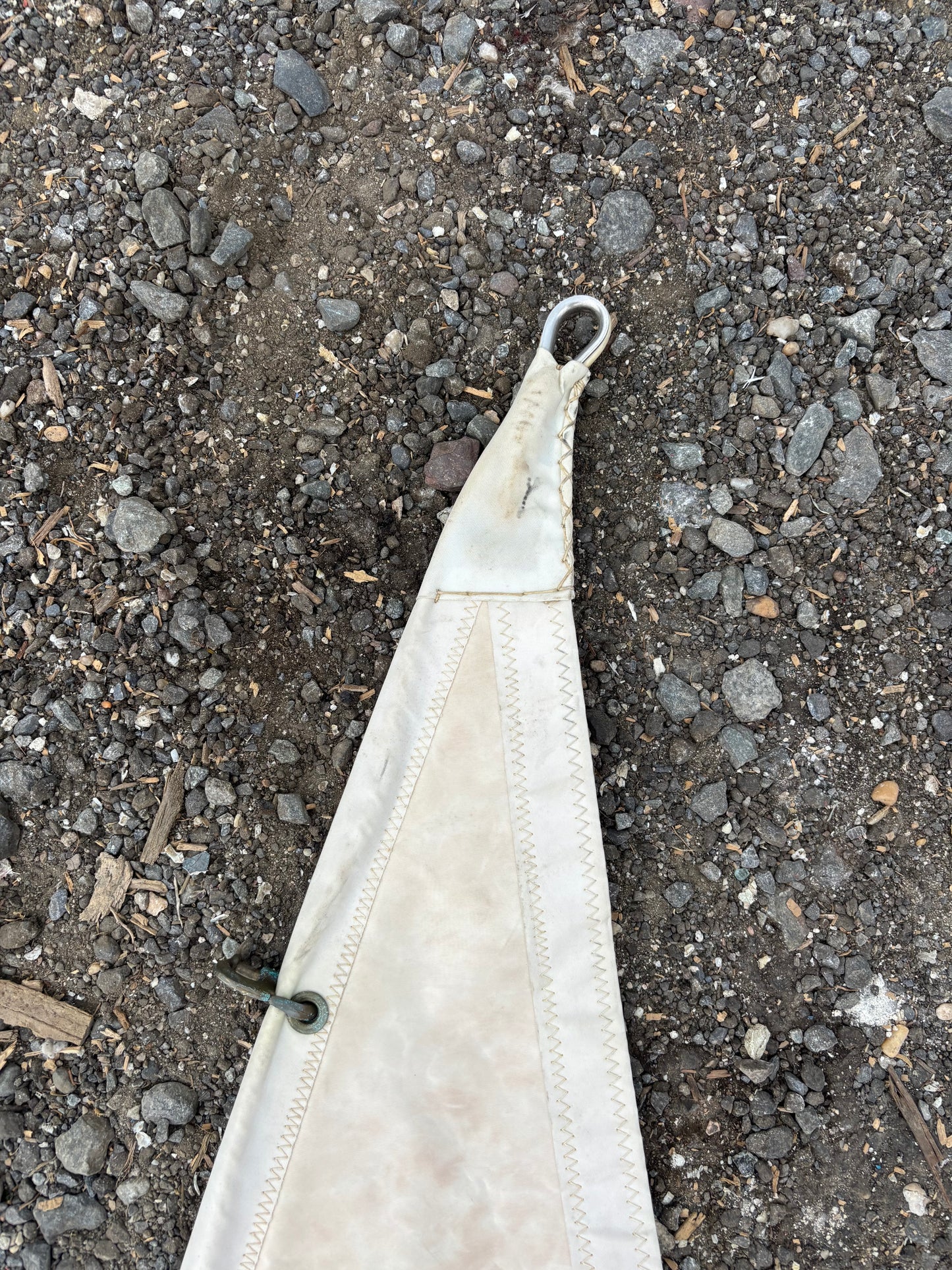 White fabric strip with a metal clip on a dark asphalt surface