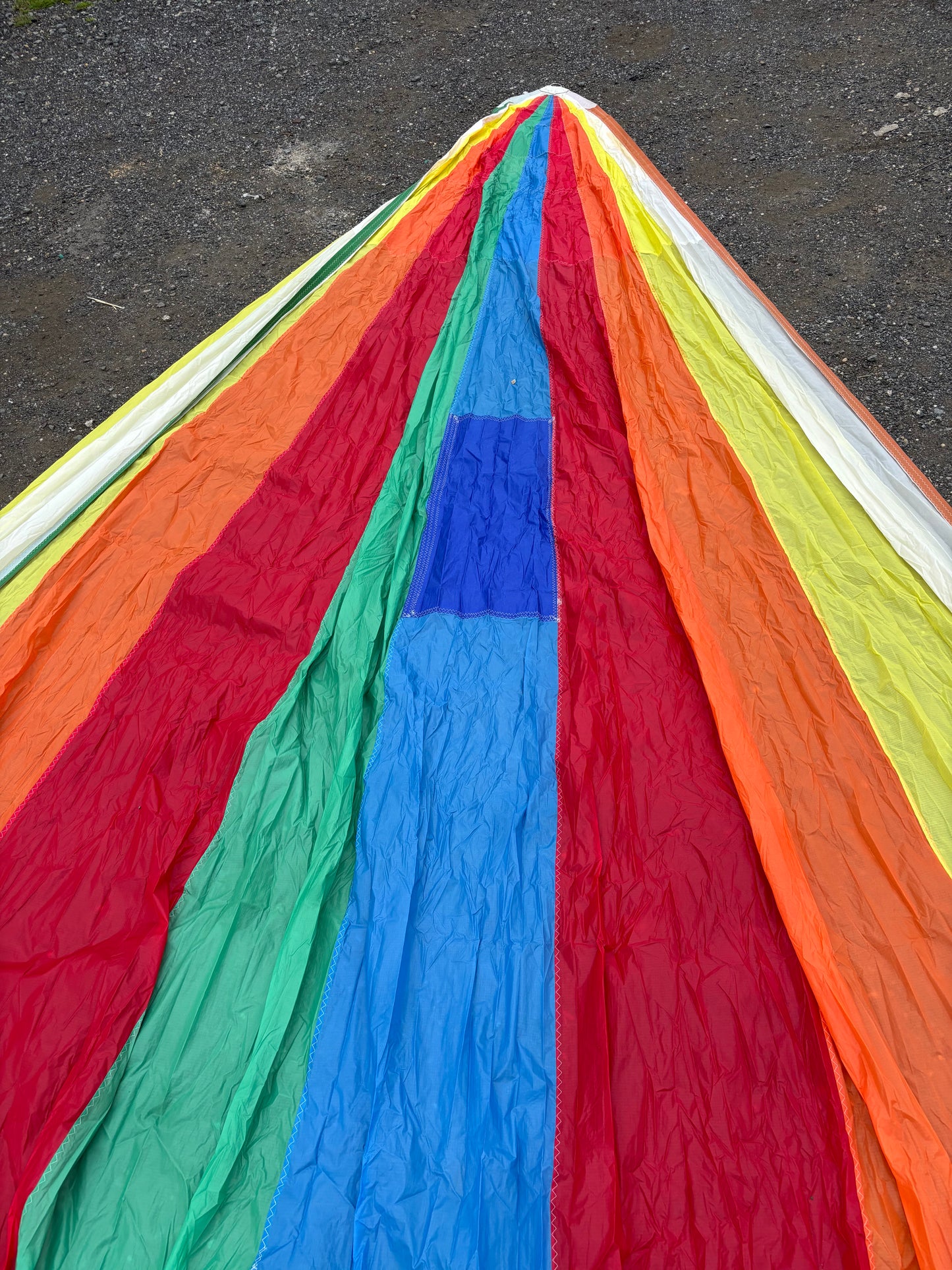 Close-up of a colorful kite with red, orange, yellow, green, blue, and purple sections on a dark surface.