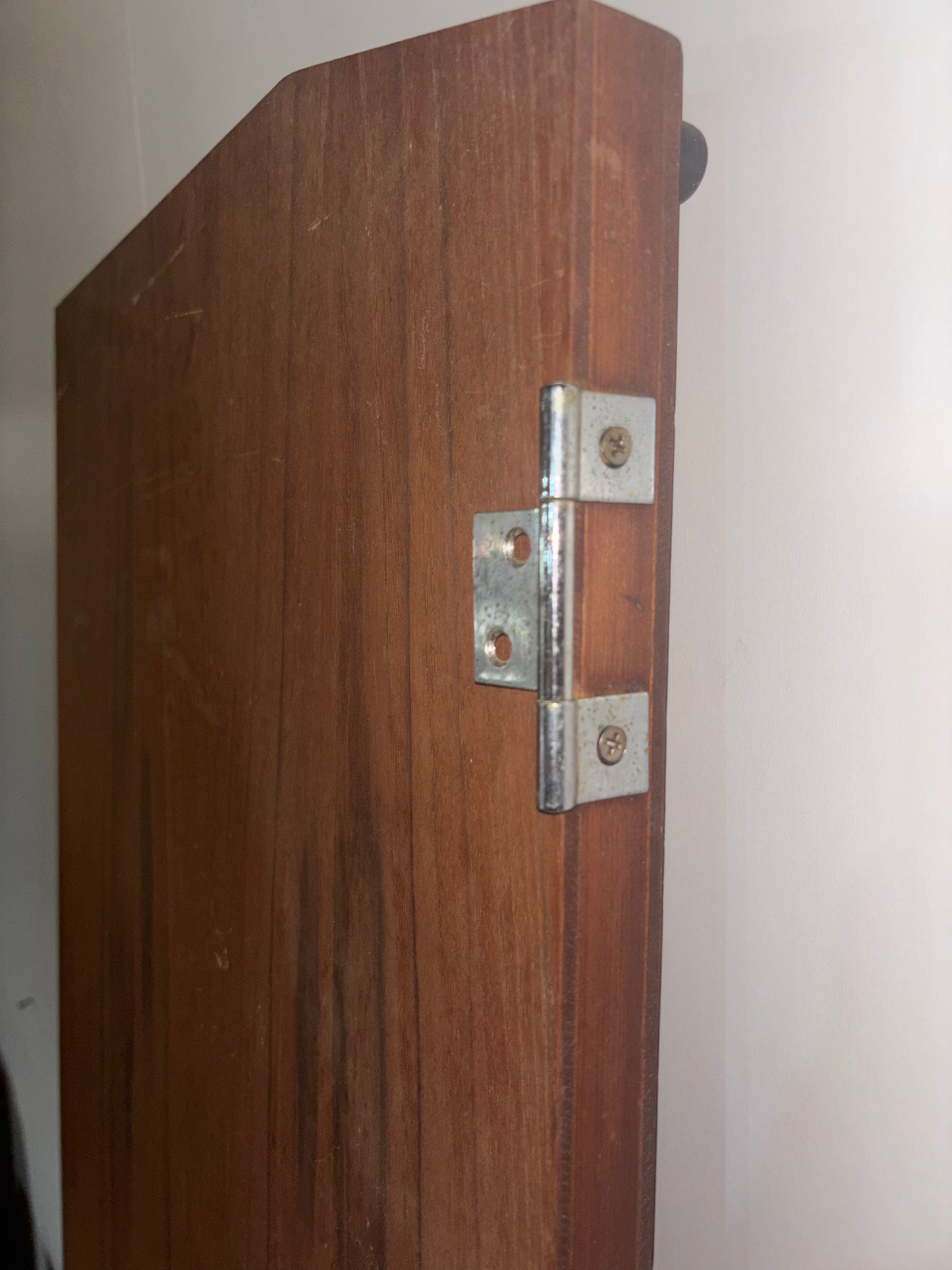 Wooden door with a metal hinge on a white wall