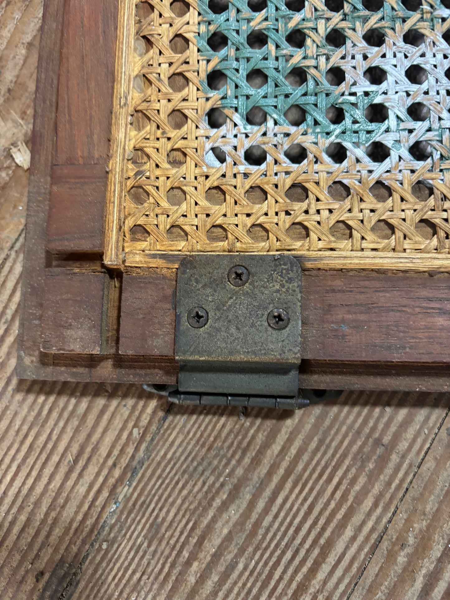 Close-up of a wooden hinge on a textured wooden surface with intricate carvings.