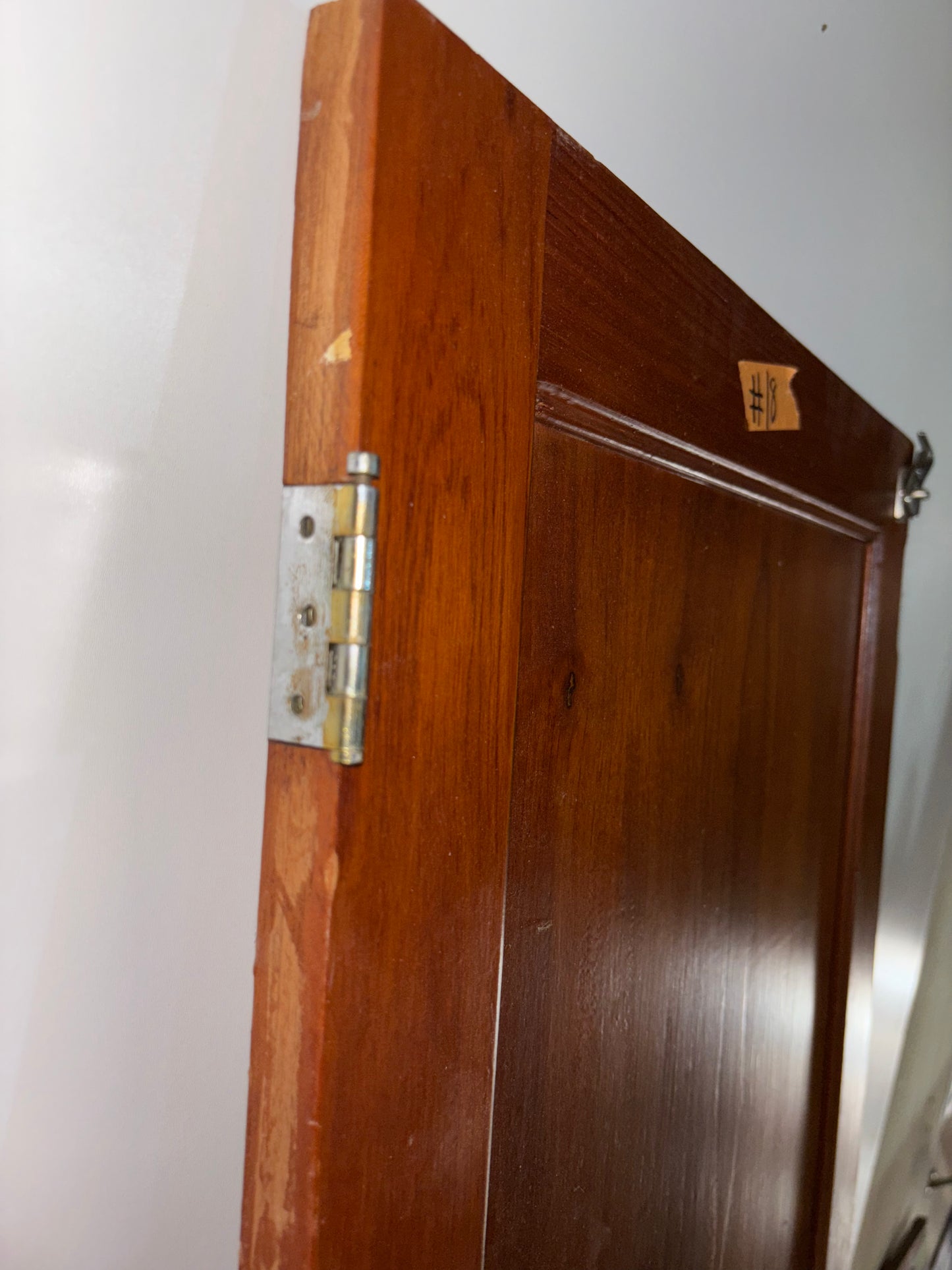 Wooden door with a hinge on a white wall