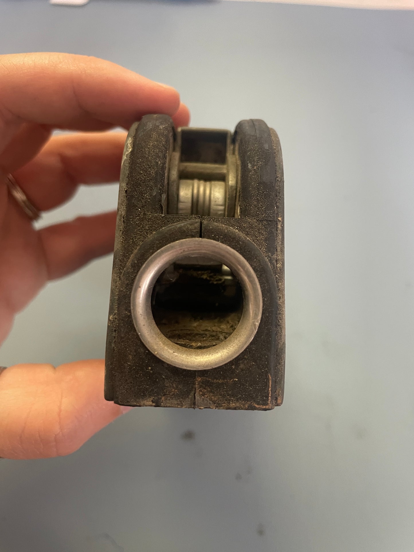 Metal mechanical component held by a hand against a plain background