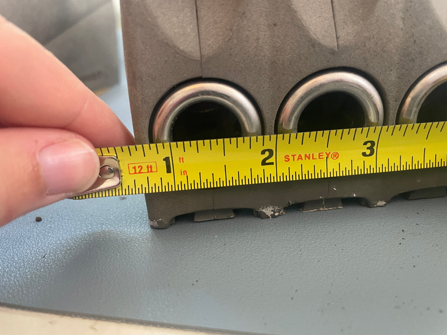 Hand using a Stanley tape measure on a mechanical component